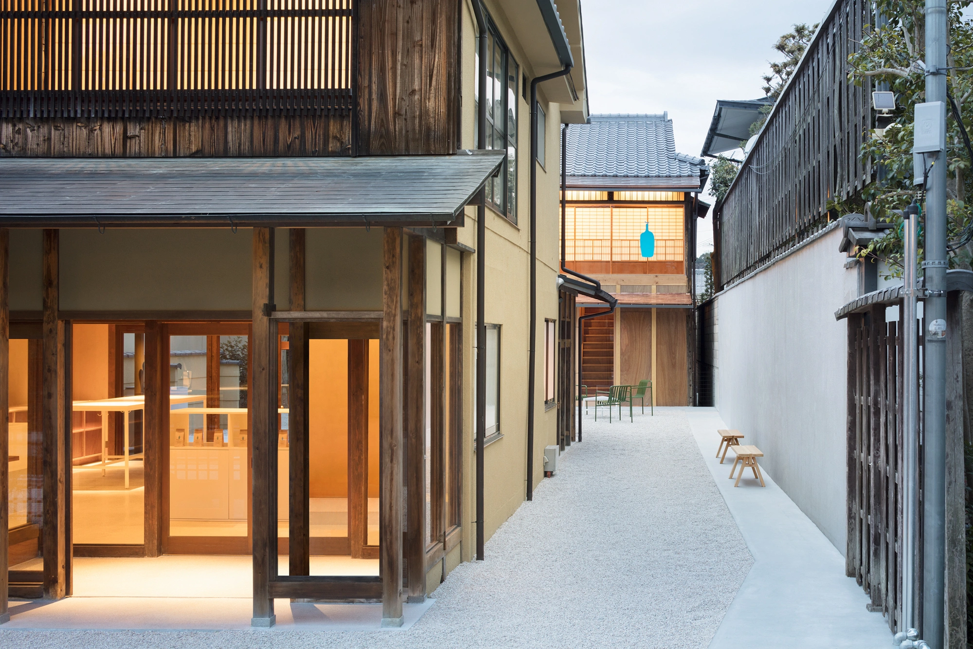 Blue Bottle Coffee Kyoto Cafe by Schemata Architects — The courtyard passage reveals the café's deliberate spatial strategy: a continuous gravel-to-terrazzo threshold dissolves the boundary between exterior and...
