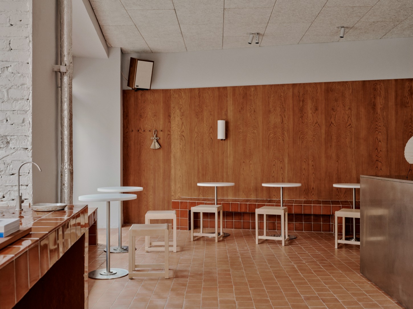 ACID Cafe by Plantea Studio by Plantea Estudio — The café interior reveals a deliberate material stratification: a herringbone-laid terracotta brick floor in warm rust tones establishes the base plane,...