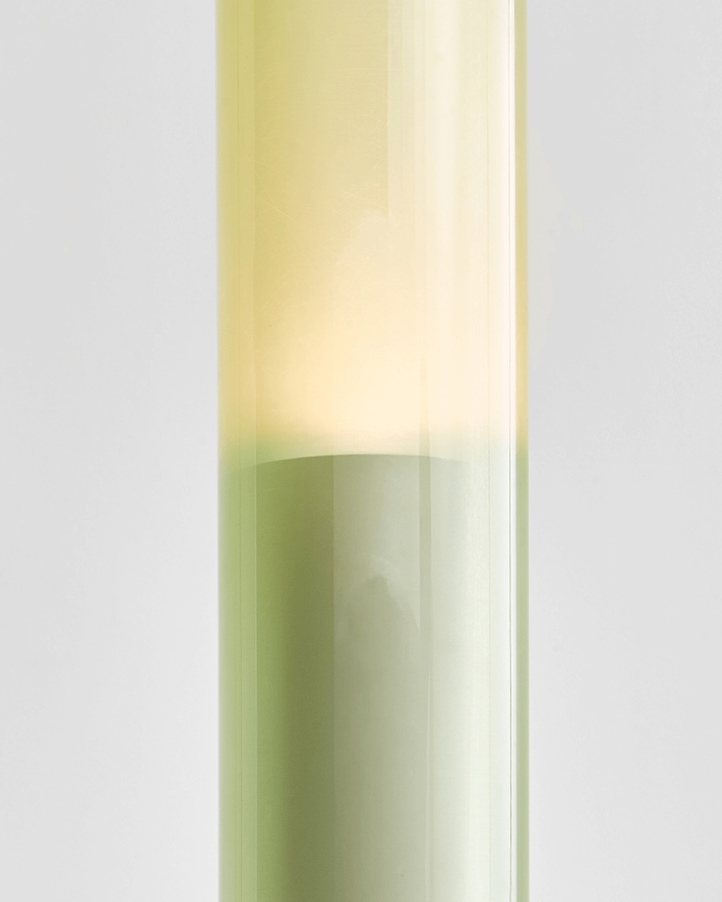 Selected Works by Forever Studio — A tall cylindrical glass vessel containing a gradient liquid that transitions from pale yellow at the top through cream and soft sage green toward the lower...