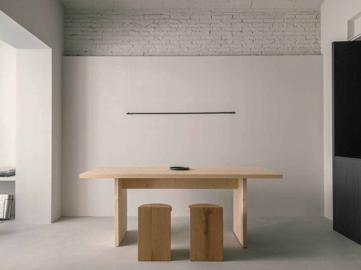 Casa Norte by CORREA Studio — Dining zone anchored by a light pine timber table with visible organic grain, positioned centrally within the unified living space.