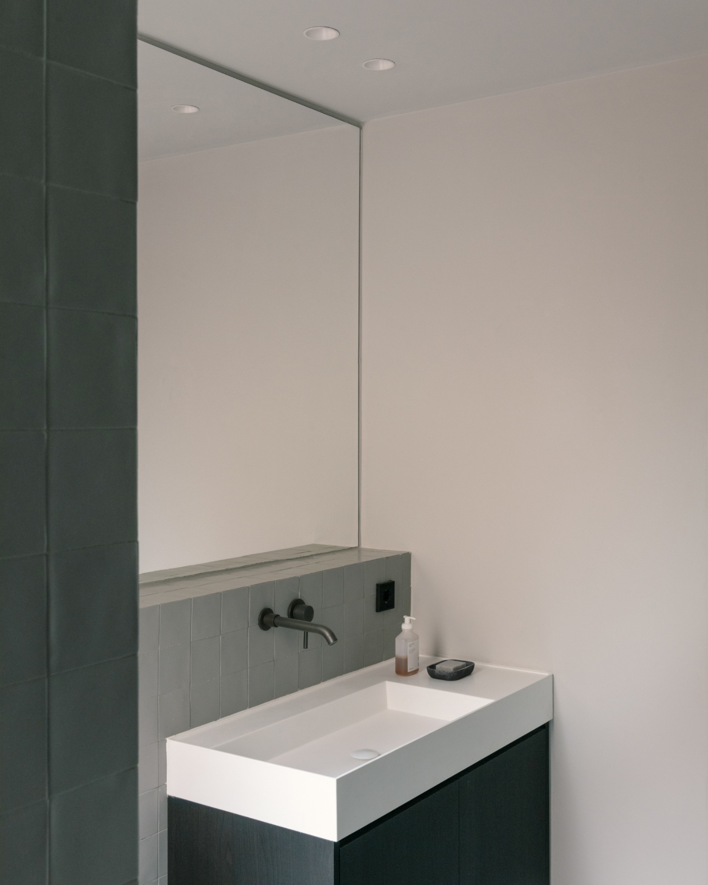 Casa Norte by CORREA Studio — A bathroom vanity in pale concrete or composite material sits beneath a large mirror that spans nearly floor-to-ceiling.