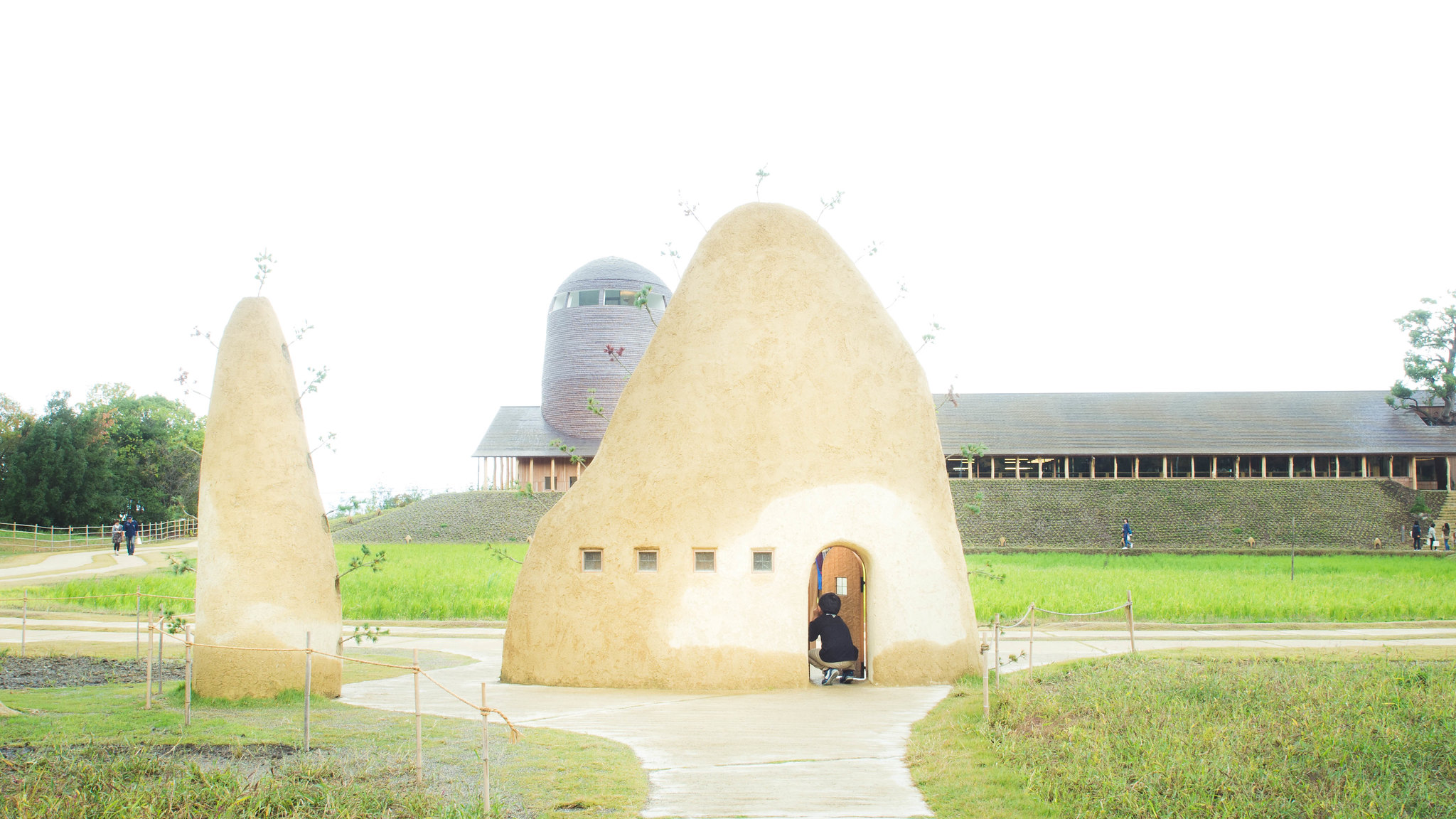La Collina Ōmi-Hachiman by Terunobu Fujimori + Michele De Lucchi — La Collina's primary structure presents as a monolithic, egg-shaped form rendered in cream-colored rammed-earth, punctuated by a wooden door and four small...