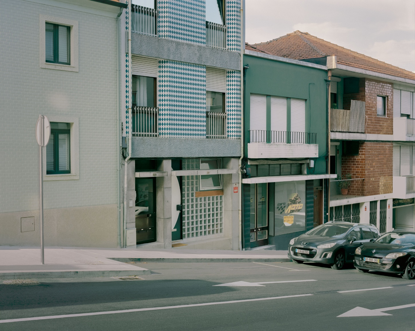 'Fireworks in White' by Willem Pab — A Porto street corner captures mixed-use residential and commercial architecture unified by a consistent teal-green palette.