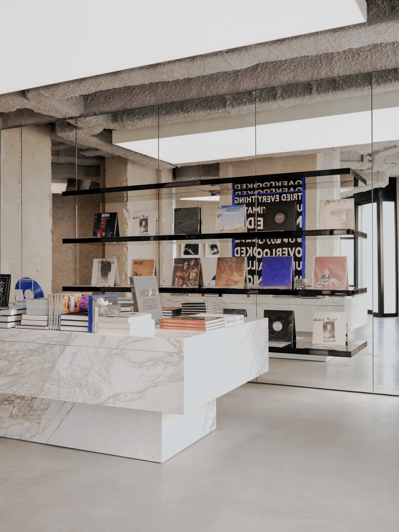 Saint Laurent Babylone in Paris — The Saint Laurent Babylone storefront features a suspended display system of black steel shelving mounted against glass, presenting books, records, and...