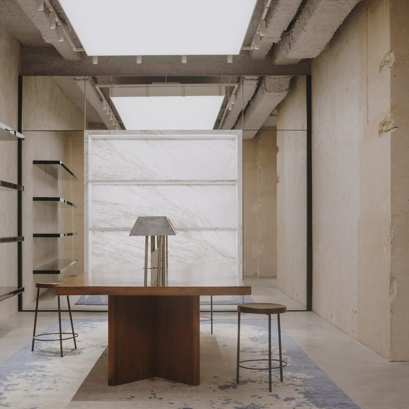Saint Laurent Babylone in Paris — A concrete-framed interior featuring a curved timber table as the compositional anchor, positioned centrally beneath an exposed concrete ceiling with...