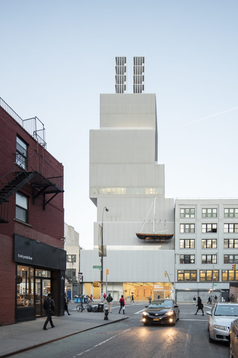 New Art Museum by SANAA — Street-level perspective captures the New Museum's stacked rectilinear volumes rising sharply above neighboring masonry structures.