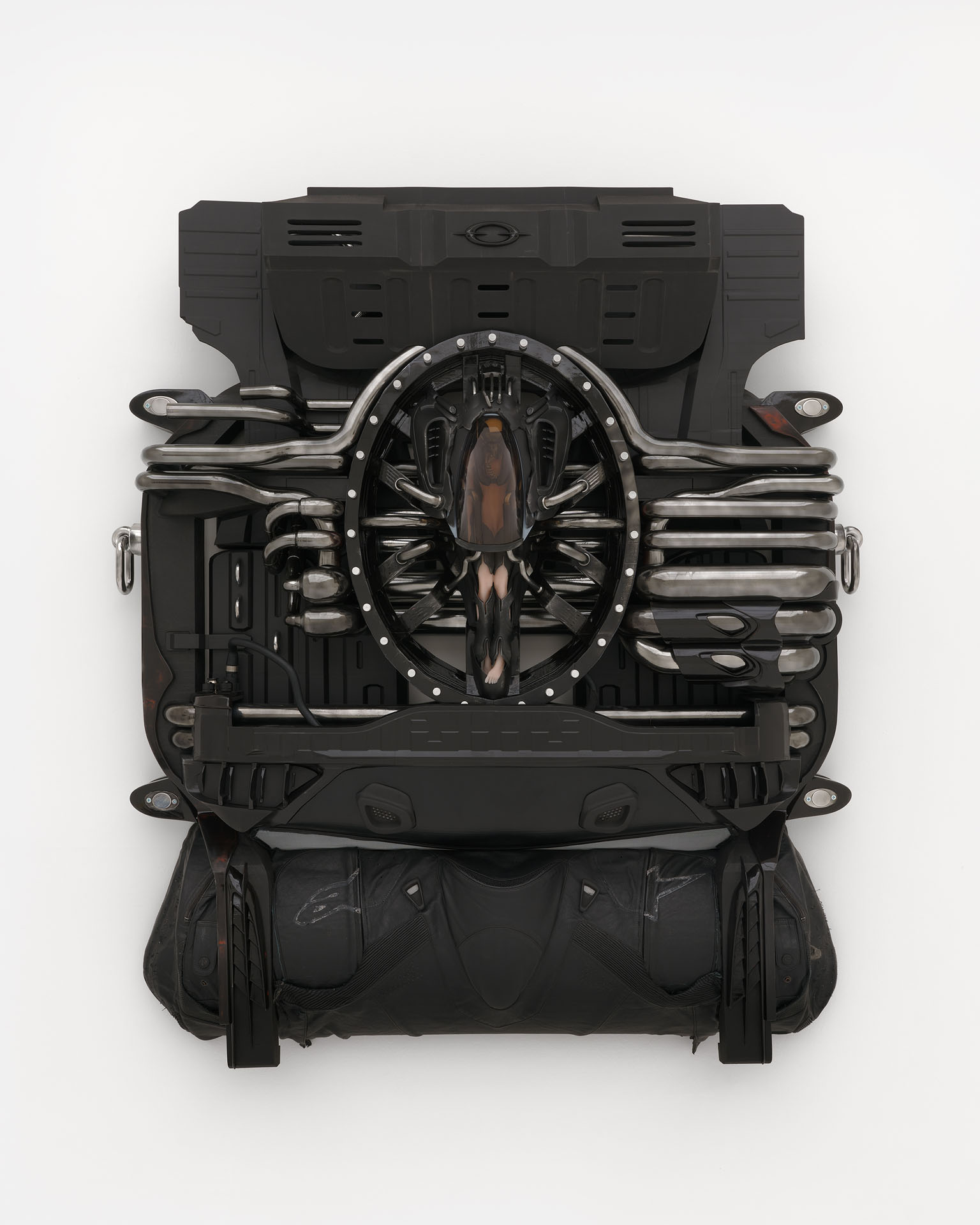 ENDO– by Taylor Ashby Hawkins at ASHES/ASHES — A wall-mounted sculptural assembly presents disassembled automotive engine components—ribbed aluminum cylinder heads and finned structures—arranged in...