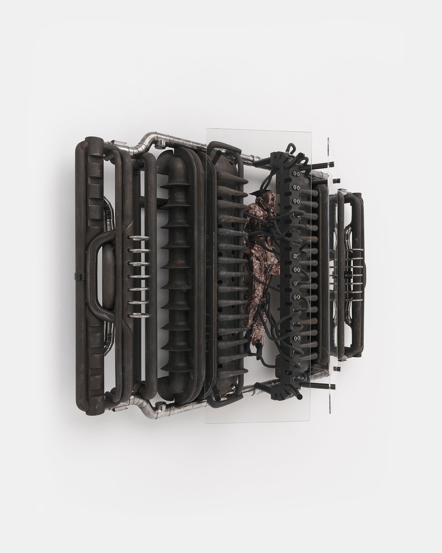 ENDO– by Taylor Ashby Hawkins at ASHES/ASHES — A wall-mounted sculptural assembly of disassembled automotive engine components—ribbed cylinder heads, finned cooling structures, and tubular...