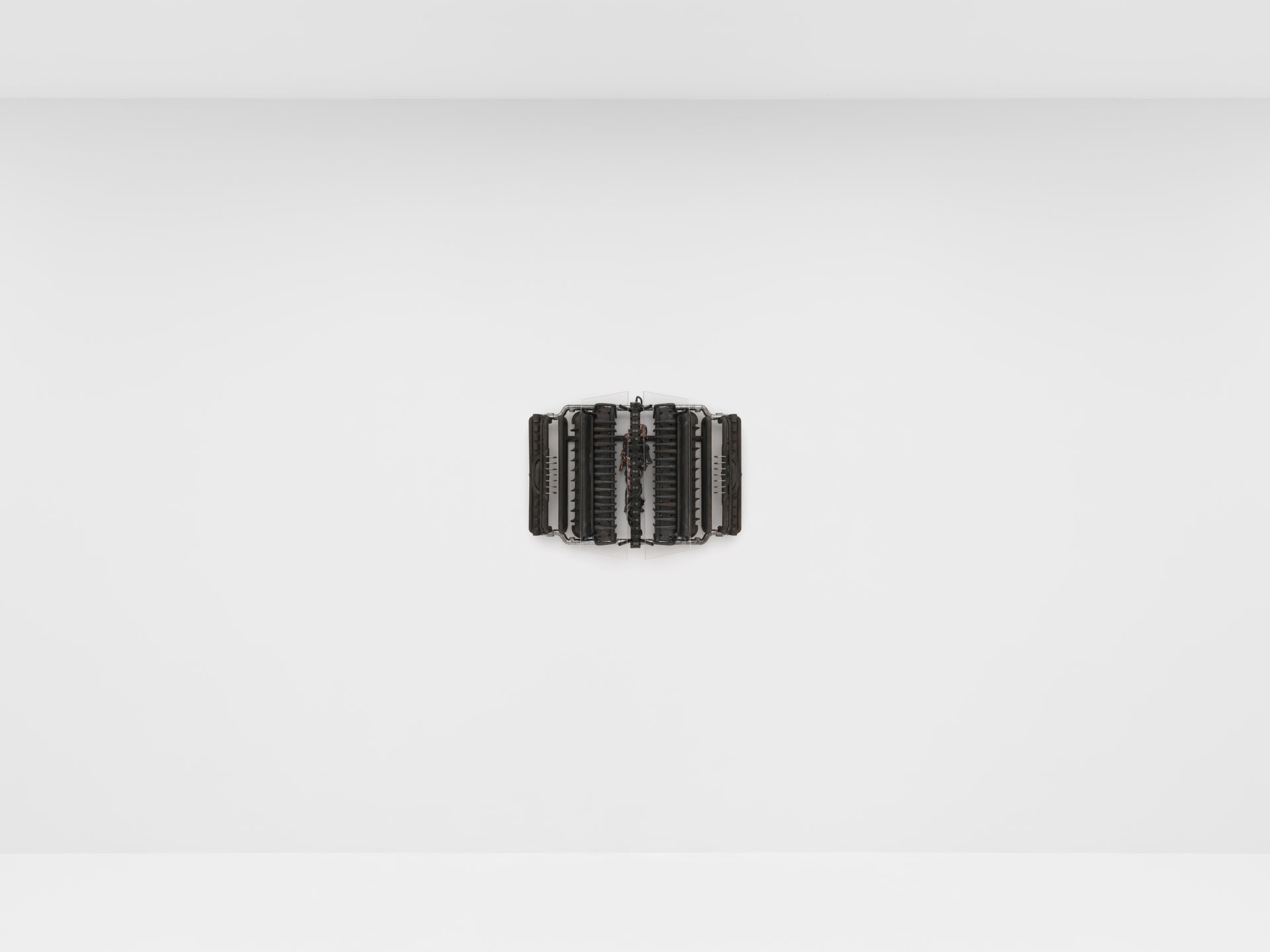 ENDO– by Taylor Ashby Hawkins at ASHES/ASHES — A symmetrical wall-mounted sculpture composed of disassembled engine components—ribbed aluminum or steel cylinder heads arranged in a radiating pattern...