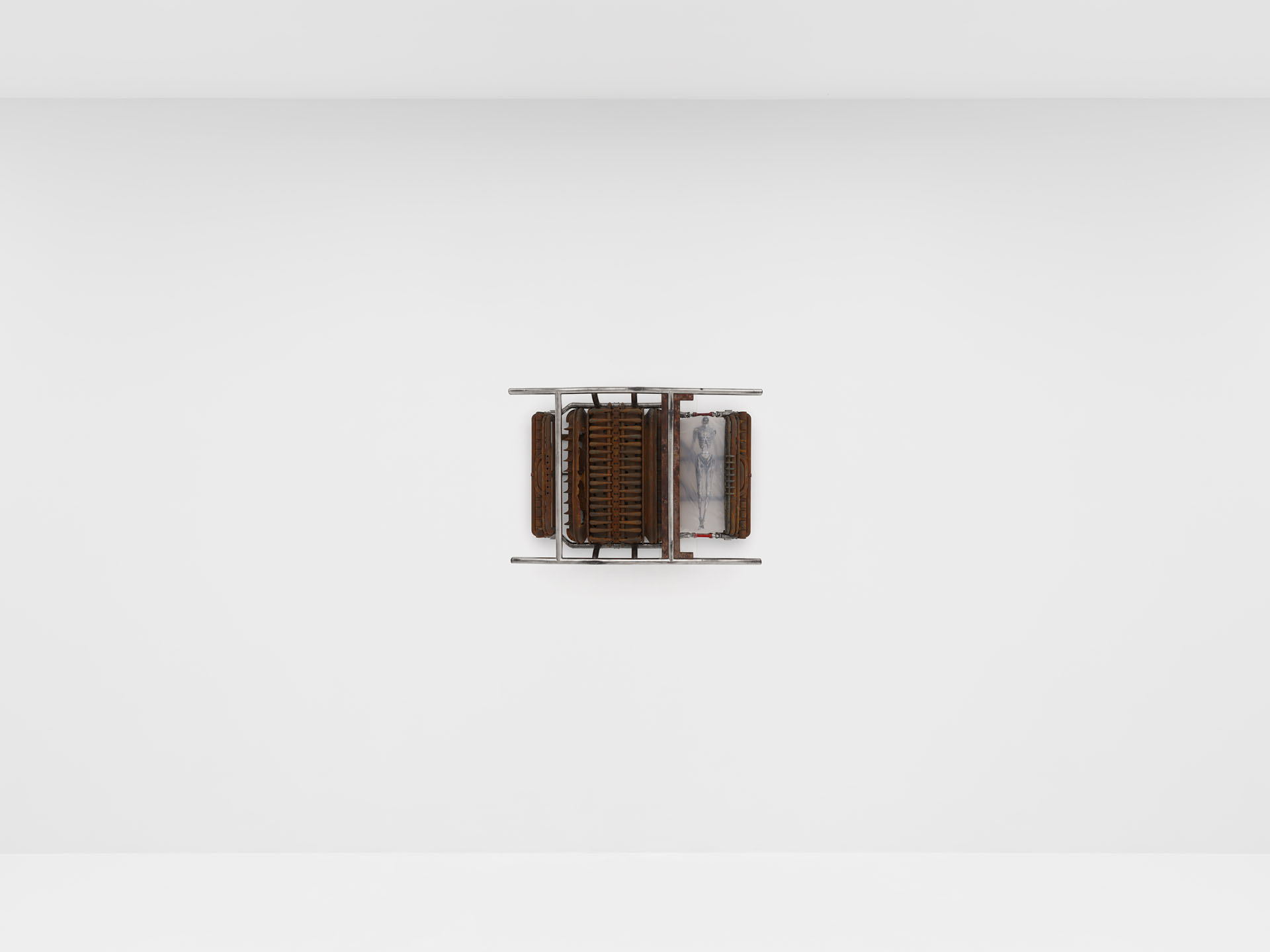 ENDO– by Taylor Ashby Hawkins at ASHES/ASHES — A wall-mounted sculptural assemblage presenting a symmetrical arrangement of ribbed metal engine components—cylindrical finned structures flanking a central...