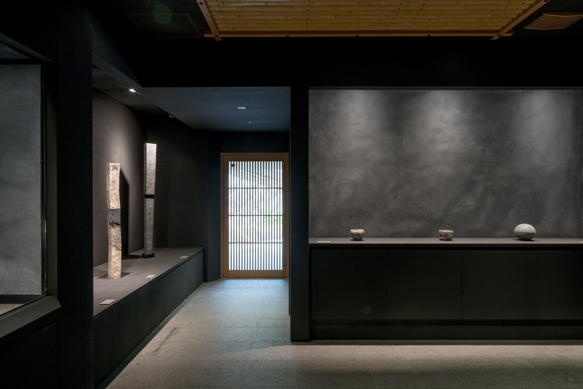 Kondo Museum in Kyoto by Mamiya Shinichi Design Studio — The gallery interior demonstrates a restrained material palette anchored by charcoal-rendered walls and recessed display shelving.