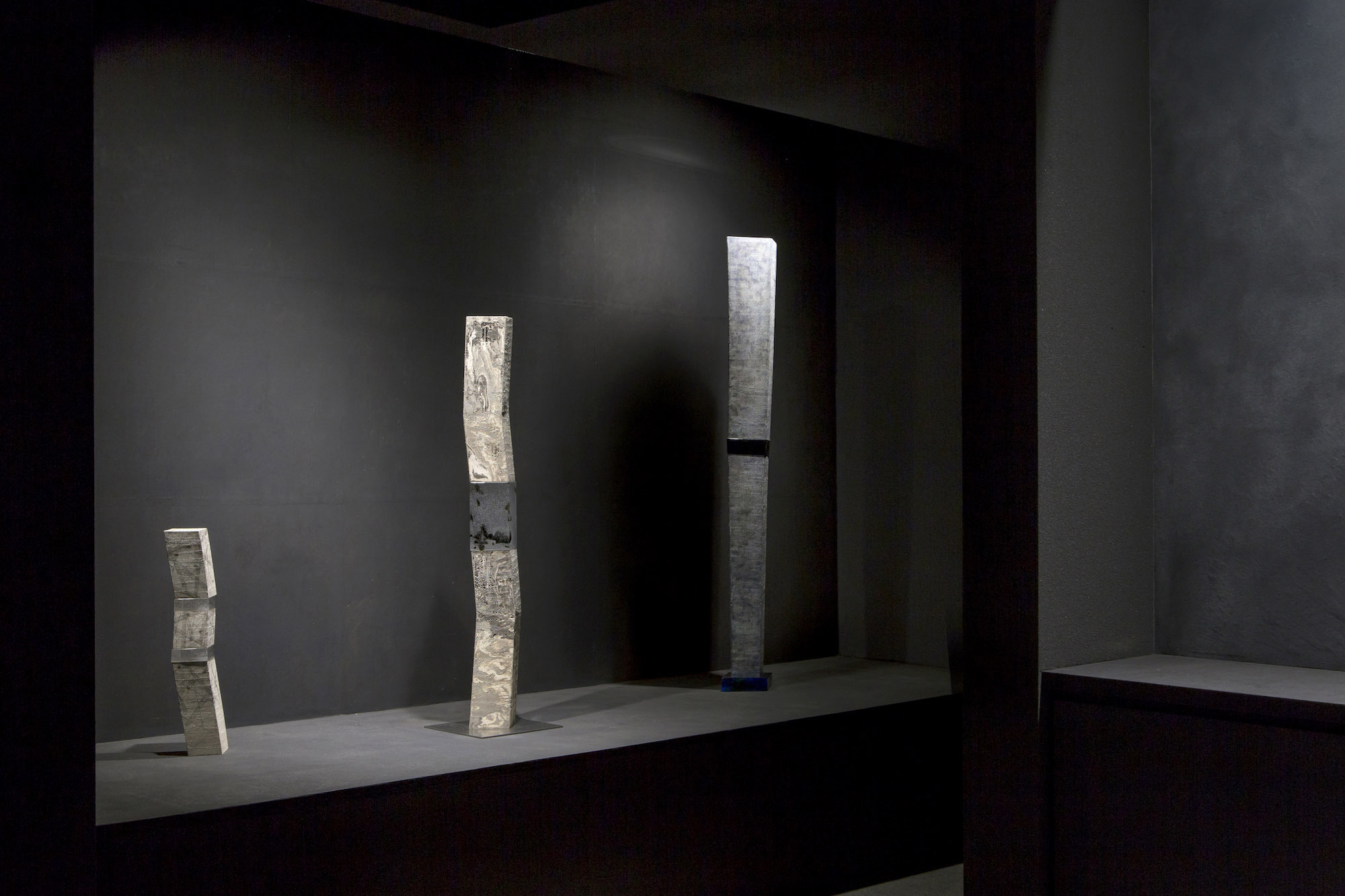 Kondo Museum in Kyoto by Mamiya Shinichi Design Studio — A gallery interior displays three vertical stone or concrete monoliths of increasing height arranged across a recessed floor platform.