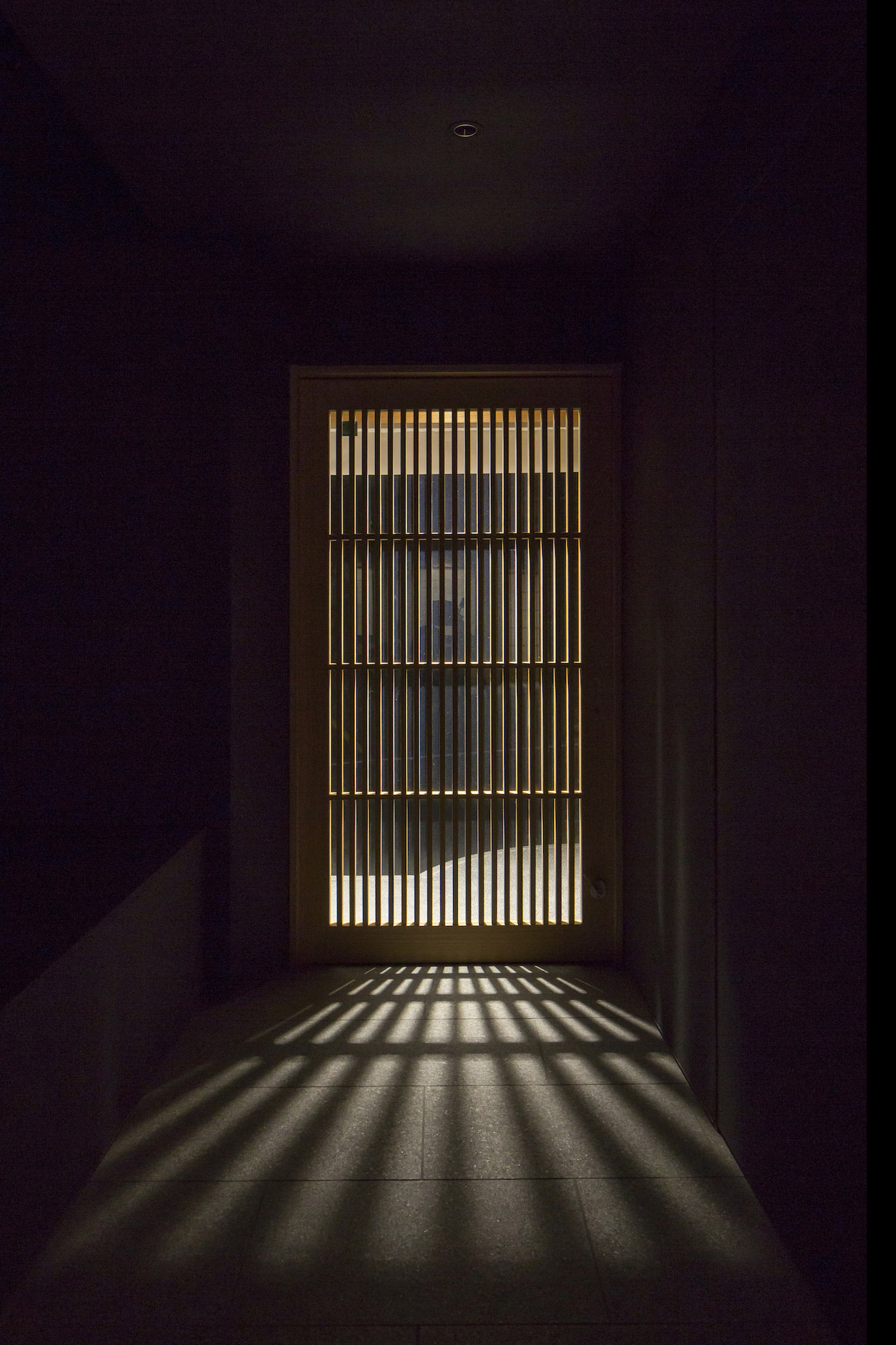 Kondo Museum in Kyoto by Mamiya Shinichi Design Studio — A narrow corridor framed by dark timber walls leads to a recessed gallery entrance.