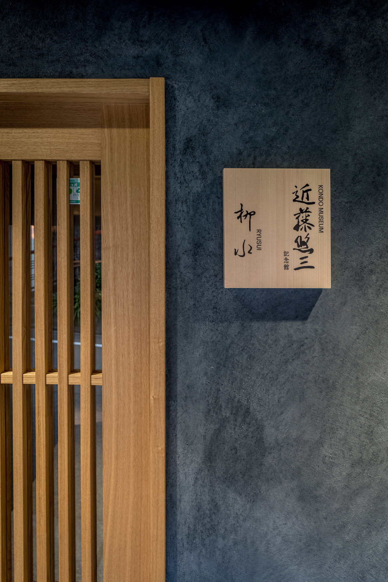 Kondo Museum in Kyoto by Mamiya Shinichi Design Studio — The museum's wooden signage identifies the institution on a weathered slate-blue rendered facade.