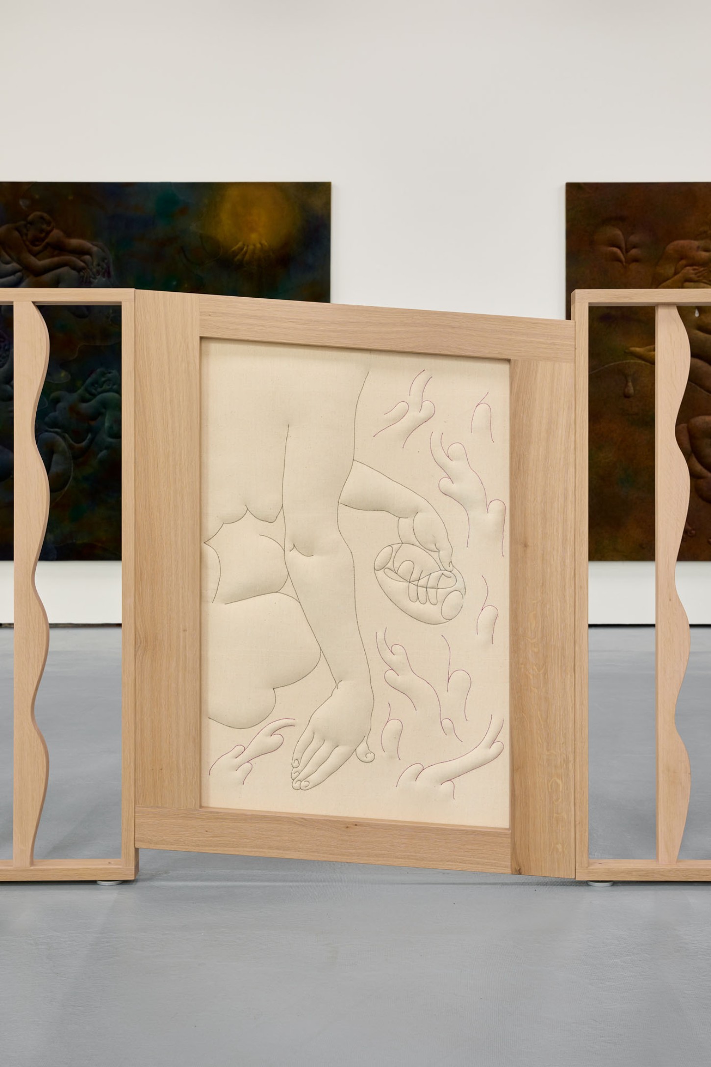 Thirst by Eliška Konečná at Polansky — Carved wood relief panel mounted within a light oak frame, displaying intertwined nude figures in recumbent poses.