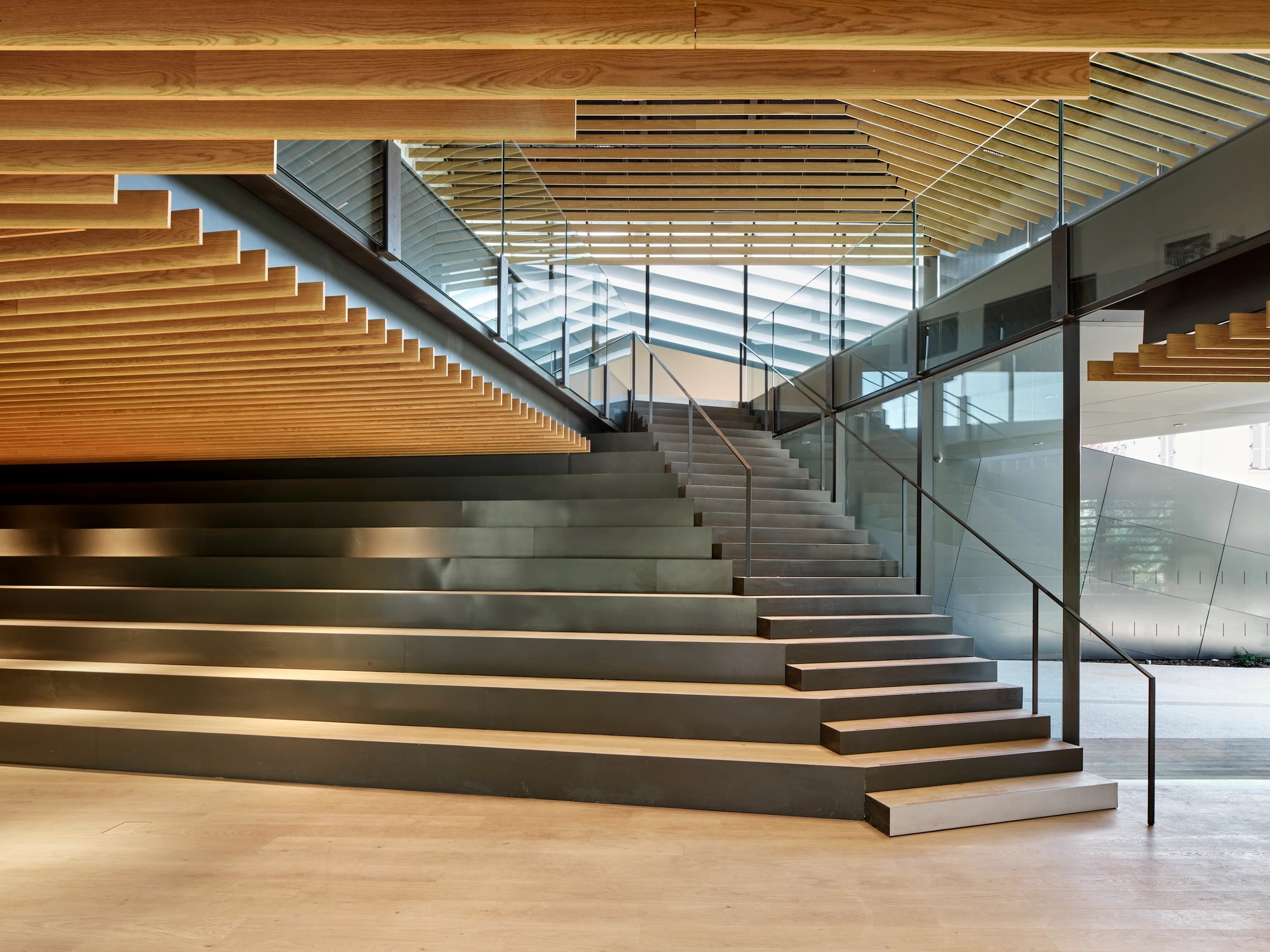 Albert Kahn Museum by Kengo Kuma & Associates — A monumental timber-clad staircase ascends through the museum's central atrium, its continuous horizontal wood striations creating rhythmic visual progression.