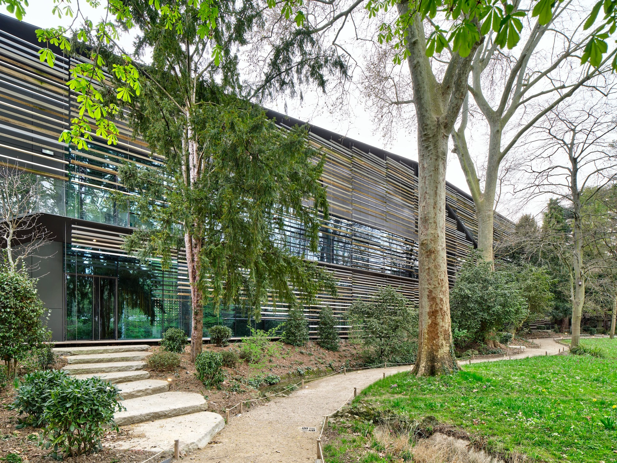 Albert Kahn Museum by Kengo Kuma & Associates — The museum's curved facade emerges from a densely wooded garden setting, its continuous horizontal aluminum striations creating rhythmic visual movement...