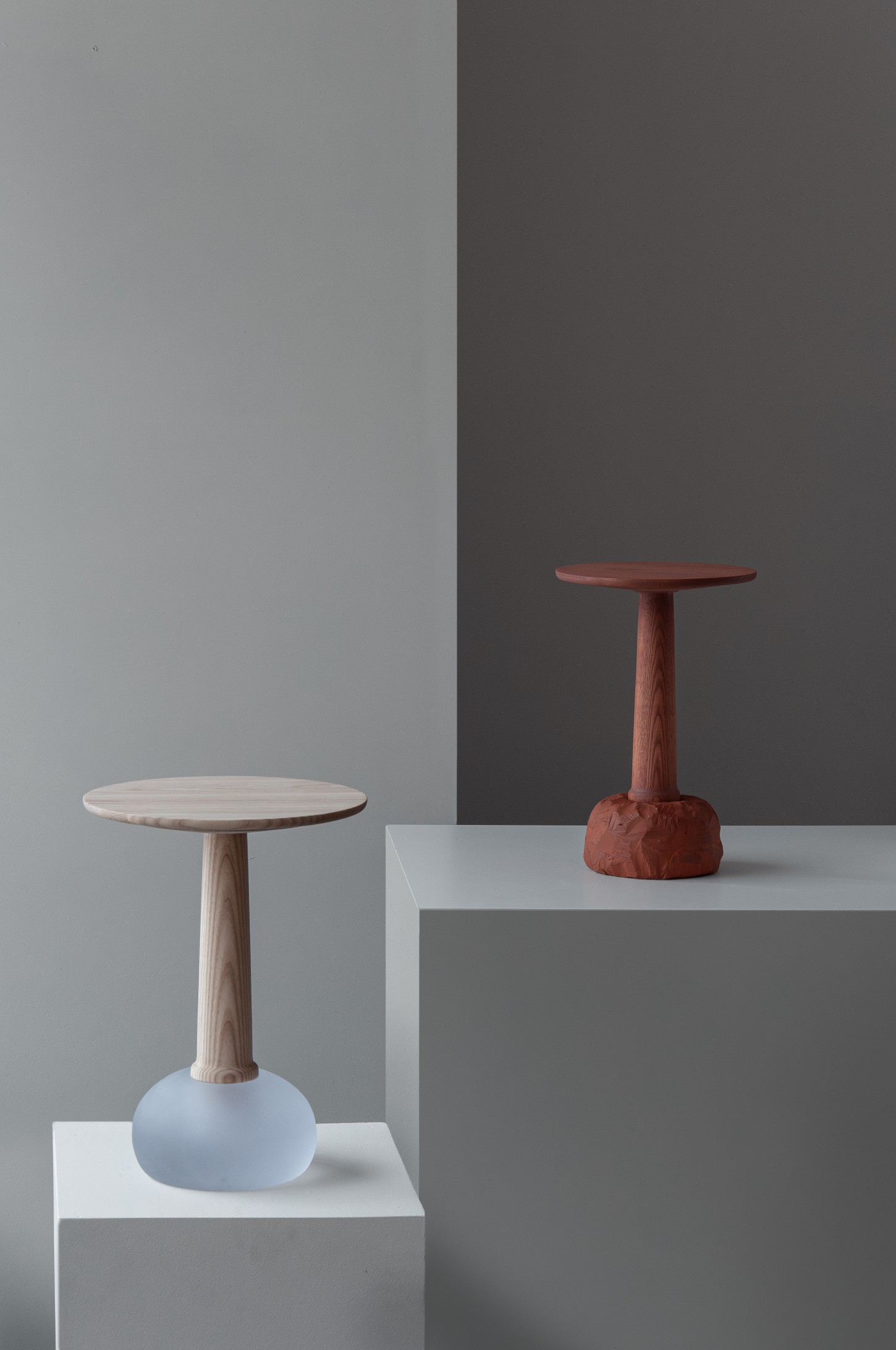 'Burn & Turn' by Adrian Bursell + Siri Svedborg — Two pedestaled tables demonstrate contrasting material approaches within the Burn & Turn collection.