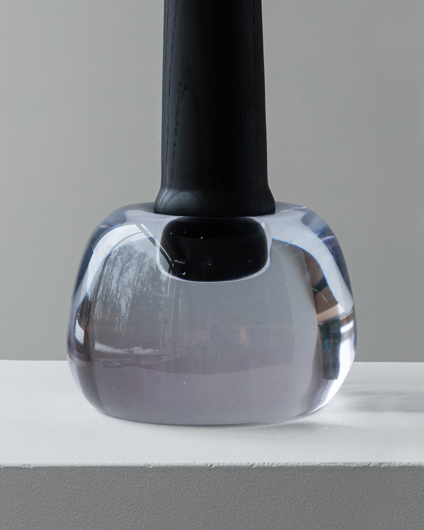 'Burn & Turn' by Adrian Bursell + Siri Svedborg — A hand-cast glass vessel in pale periwinkle sits atop a turned timber pedestal, its molten surface irregular and asymmetrical.