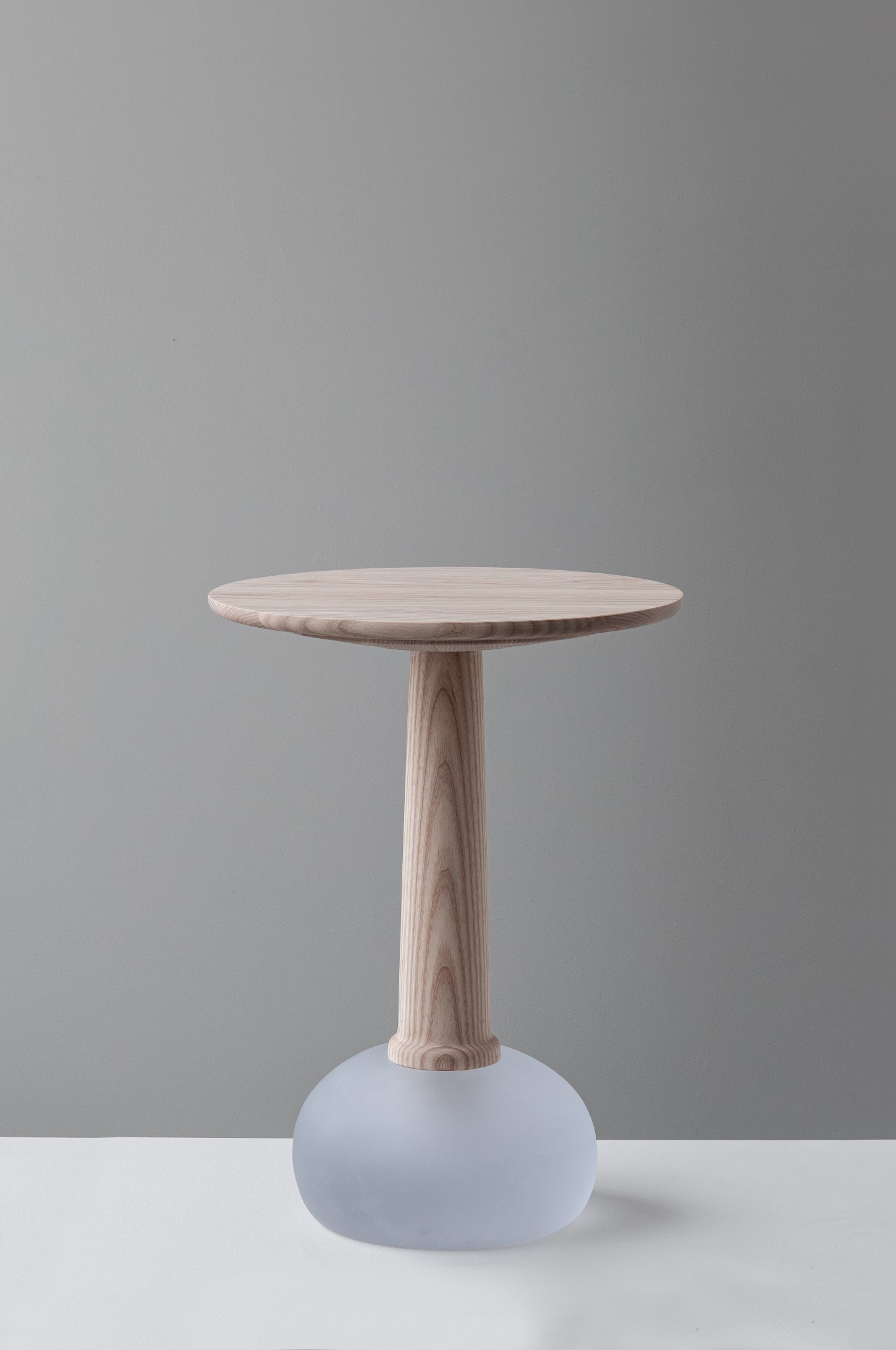 'Burn & Turn' by Adrian Bursell + Siri Svedborg — A pedestal table from 'Burn & Turn' combines turned timber and hand-cast glass in deliberate material contrast.