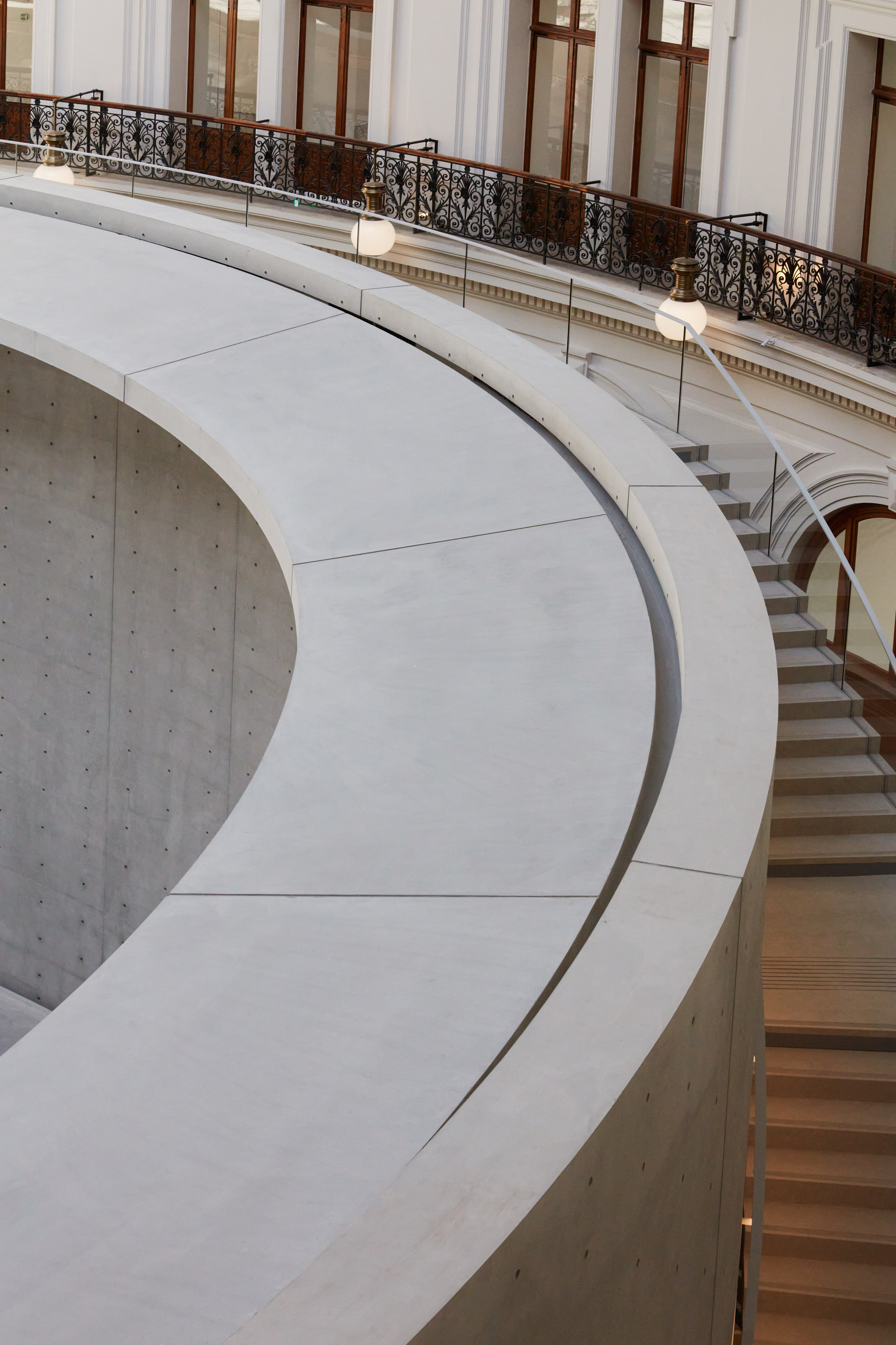 Paris' La Bourse de Commerce redesigned by Tadao Ando — A close-up view of the monolithic concrete cylinder that anchors the rotunda's void, its curved surface segmented by precise joints and rising nine meters...