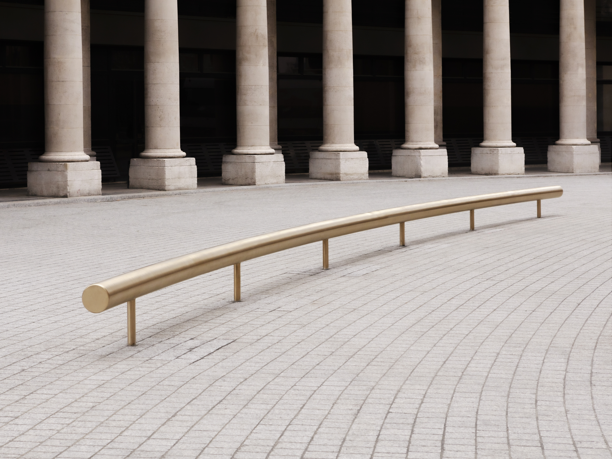 Paris' La Bourse de Commerce redesigned by Tadao Ando — A brass handrail curves gently across the geometric paving of La Bourse de Commerce's courtyard, its polished cylindrical form echoing the minimalist...