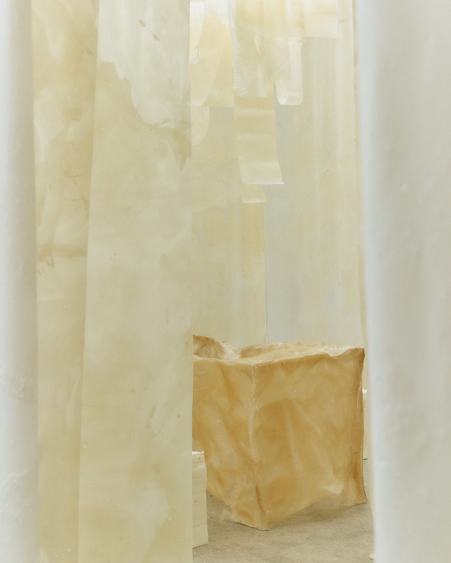 'White Utopia' by Natural Material Studio — A sealed kraft paper package sits on polished concrete within a minimalist interior passage.