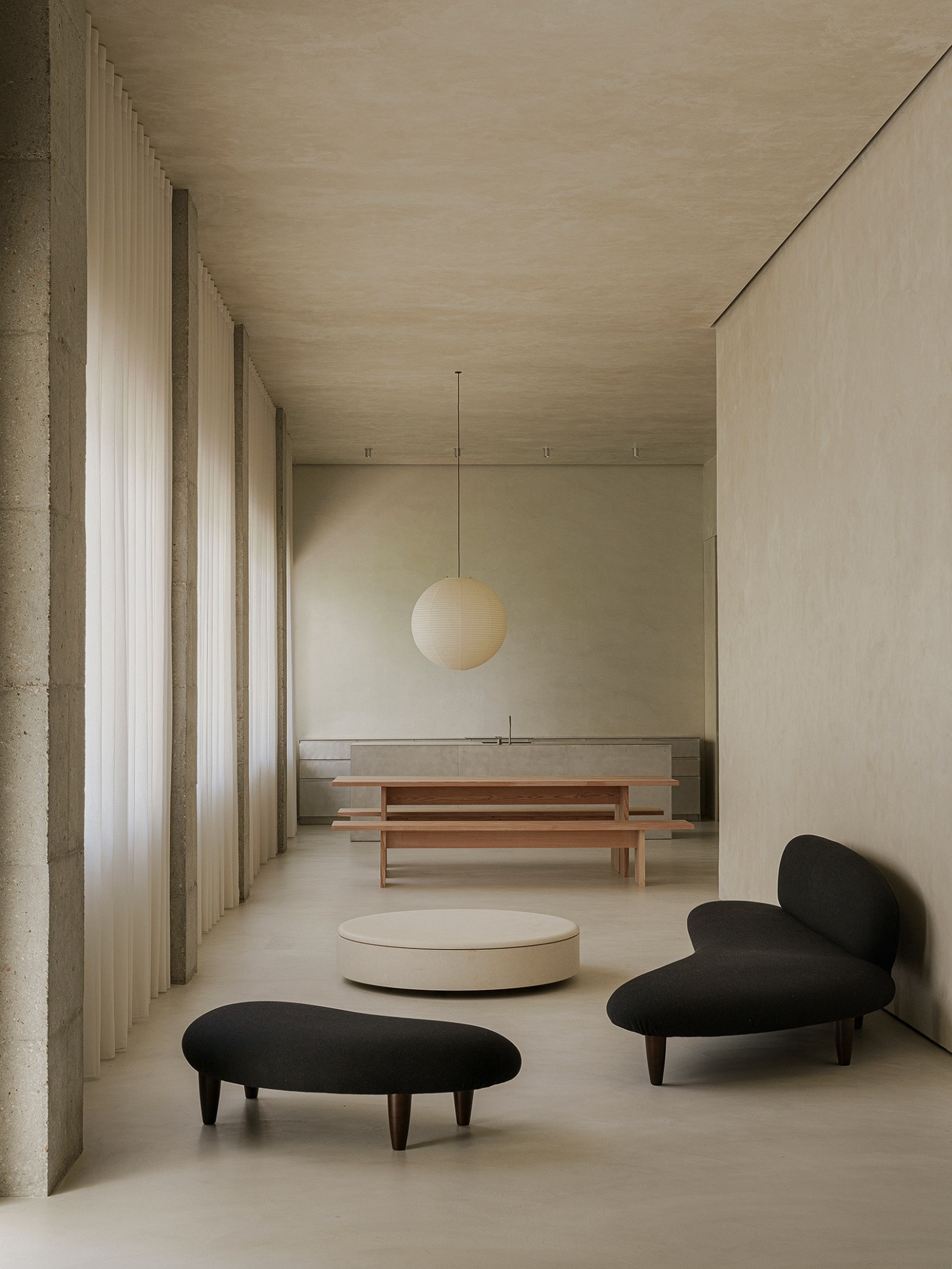 ZØ Residence by Studio Beta Ø — A minimalist corridor space anchored by two black organic-form chairs with tapered wooden legs flanking a cream circular platform.