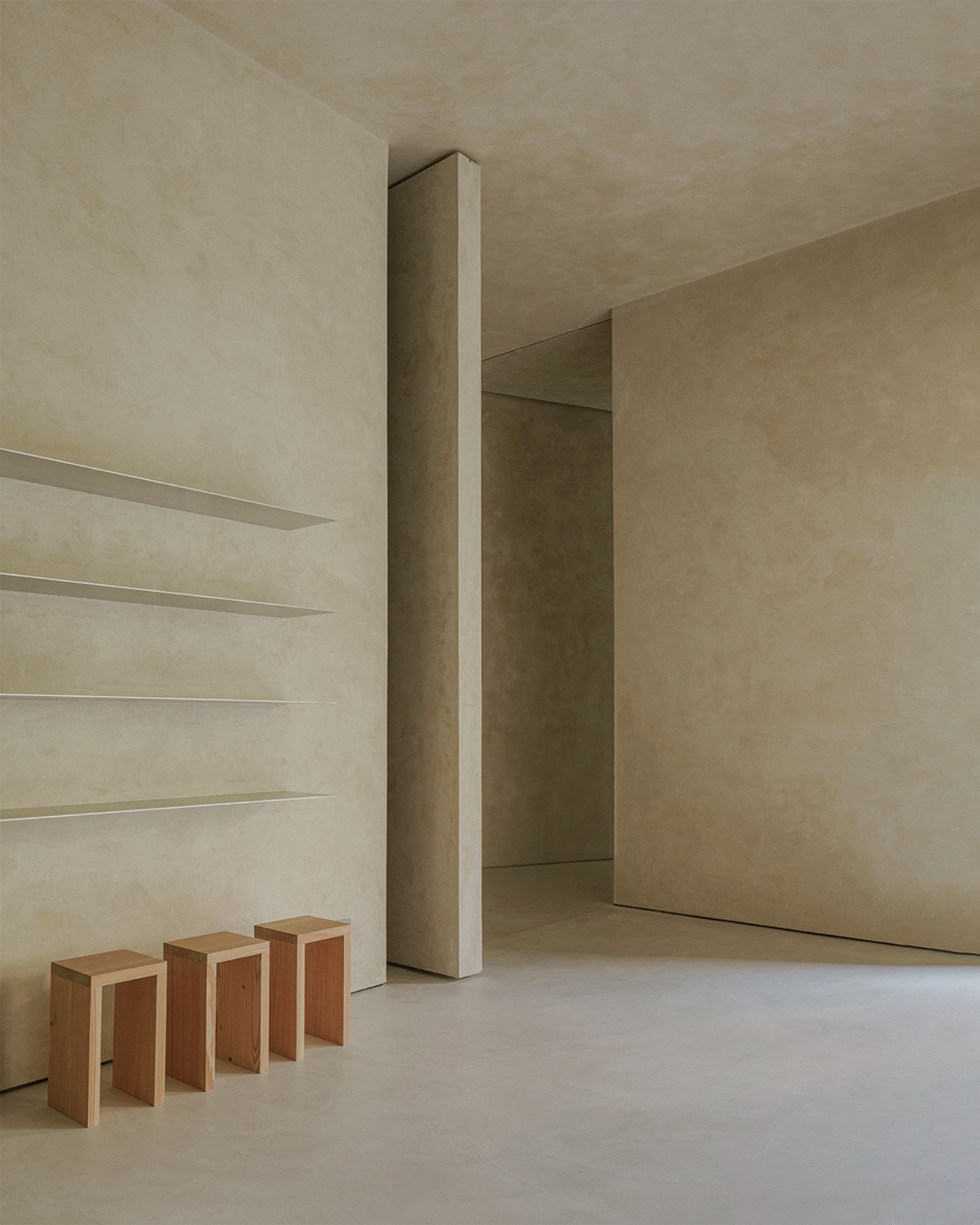ZØ Residence by Studio Beta Ø — A minimalist interior passage defined by a tall monolithic concrete column rising from floor to ceiling, bisecting the space into distinct zones.