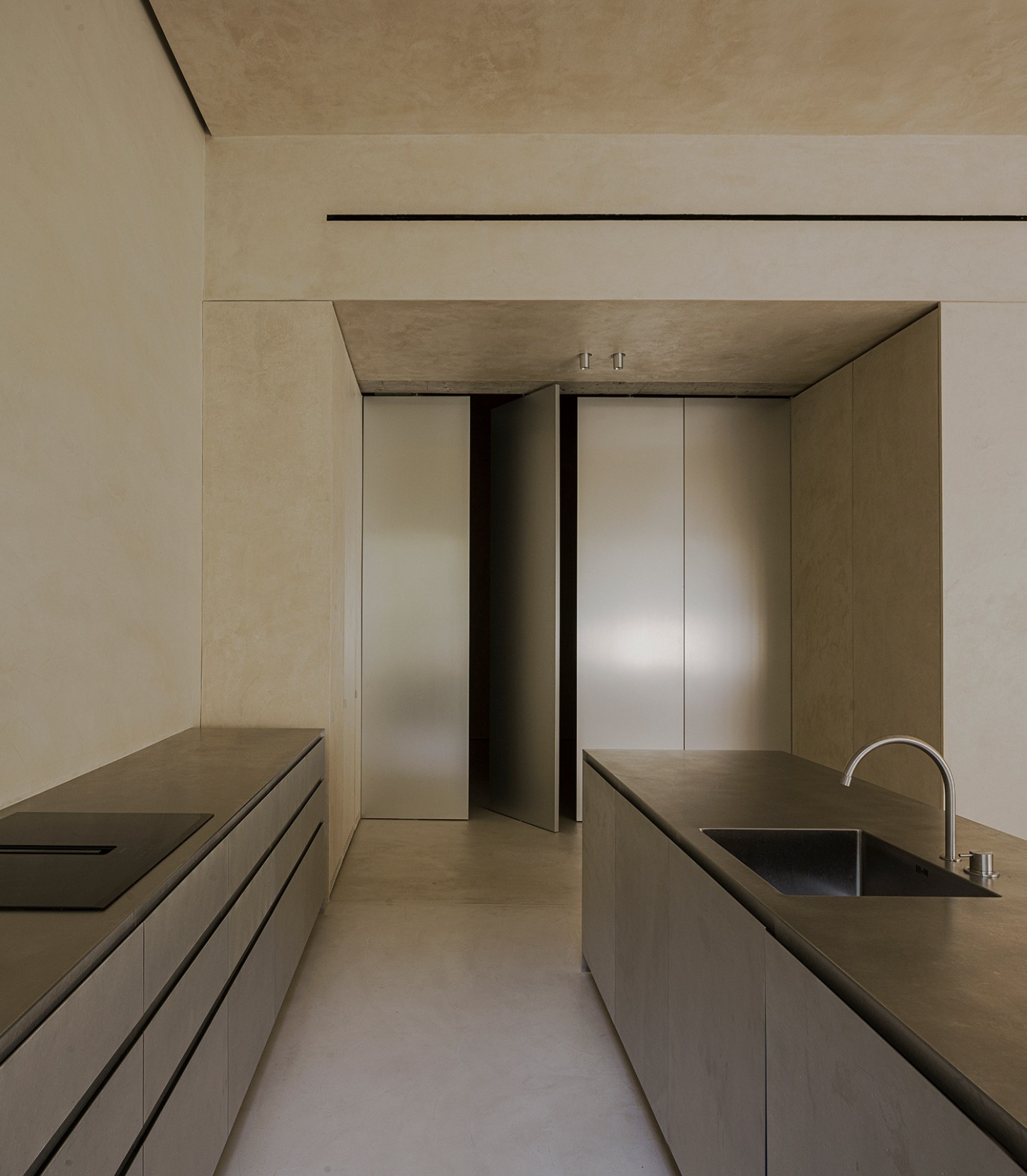ZØ Residence by Studio Beta Ø — A galley kitchen rendered in continuous timber cabinetry with integrated sink and minimal hardware.