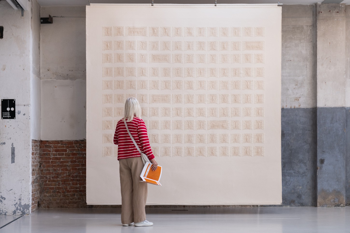 'Repetition is a Form of Change' by Sophie Rowley at Looiersgracht 60 — A large-scale textile work composed of approximately 120 woven units arranged in a 12-row grid dominates the gallery wall.