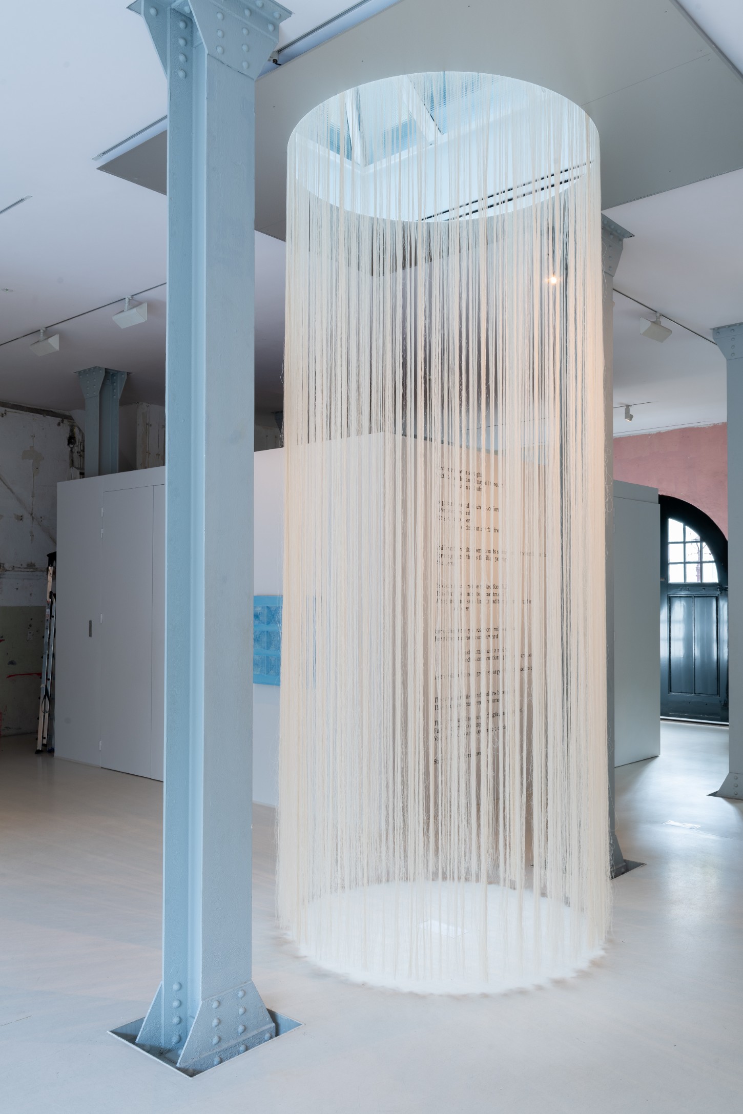 'Repetition is a Form of Change' by Sophie Rowley at Looiersgracht 60 — A cylindrical installation suspended from the ceiling comprises approximately 120 cream-colored woven textile units arranged in a grid pattern.