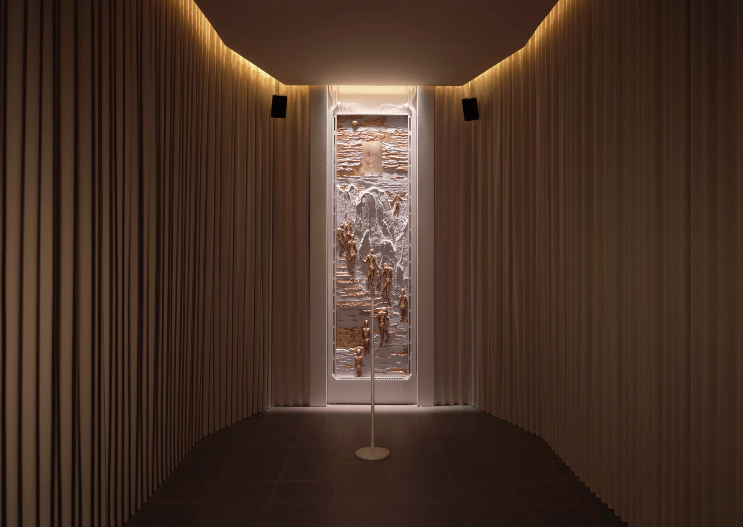 The Call by Holly Herndon & Mat Dryhurst at Serpentine North — A narrow corridor lined with vertical ribbed plaster panels in cream and taupe tones creates a compressed spatial perspective.