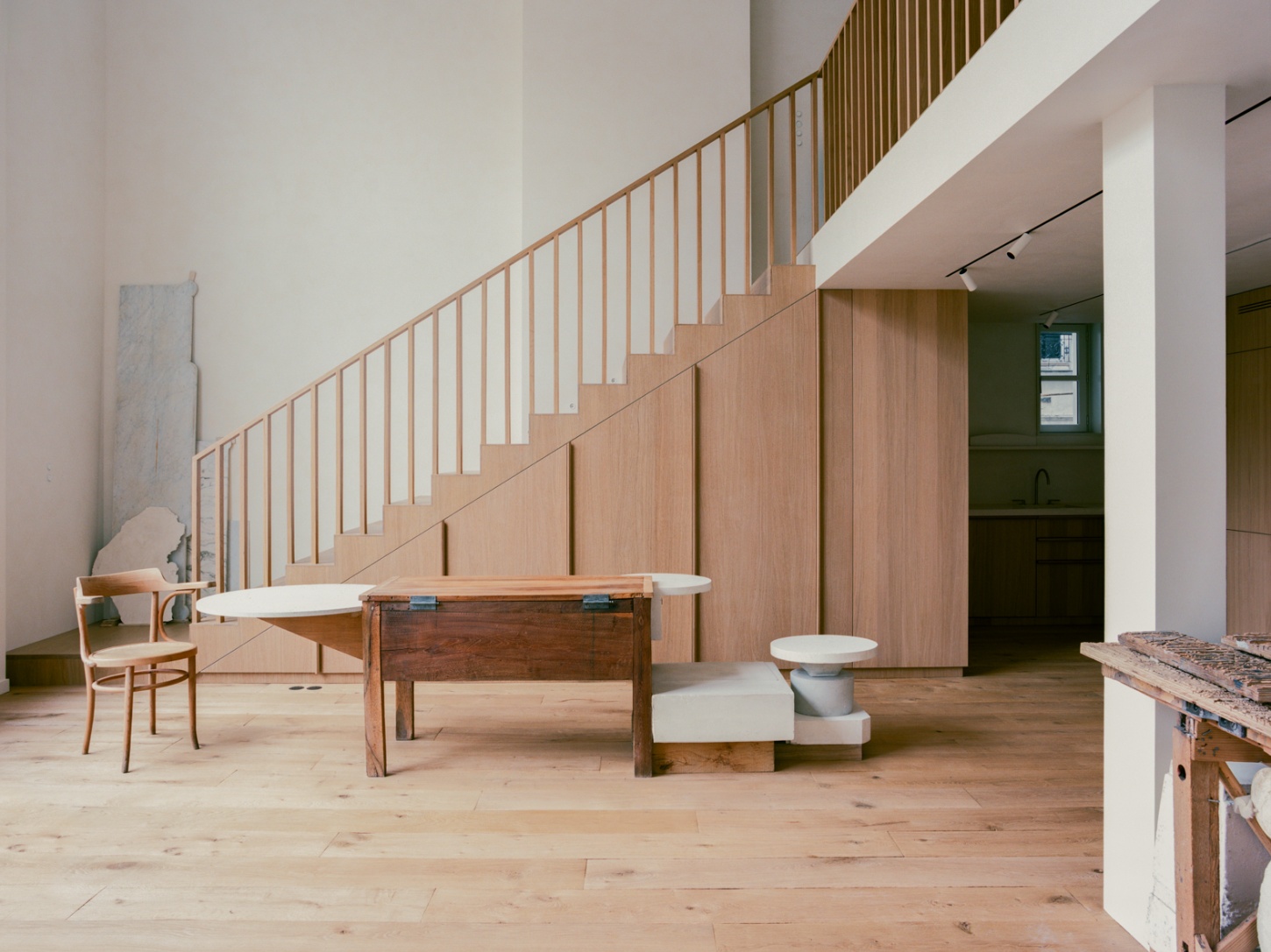 Casey Casey Showroom by Atelier NEA — The showroom's central volume features a pine floorboard expanse anchored by functional display elements: a wooden table with geometric X-frame base, two...