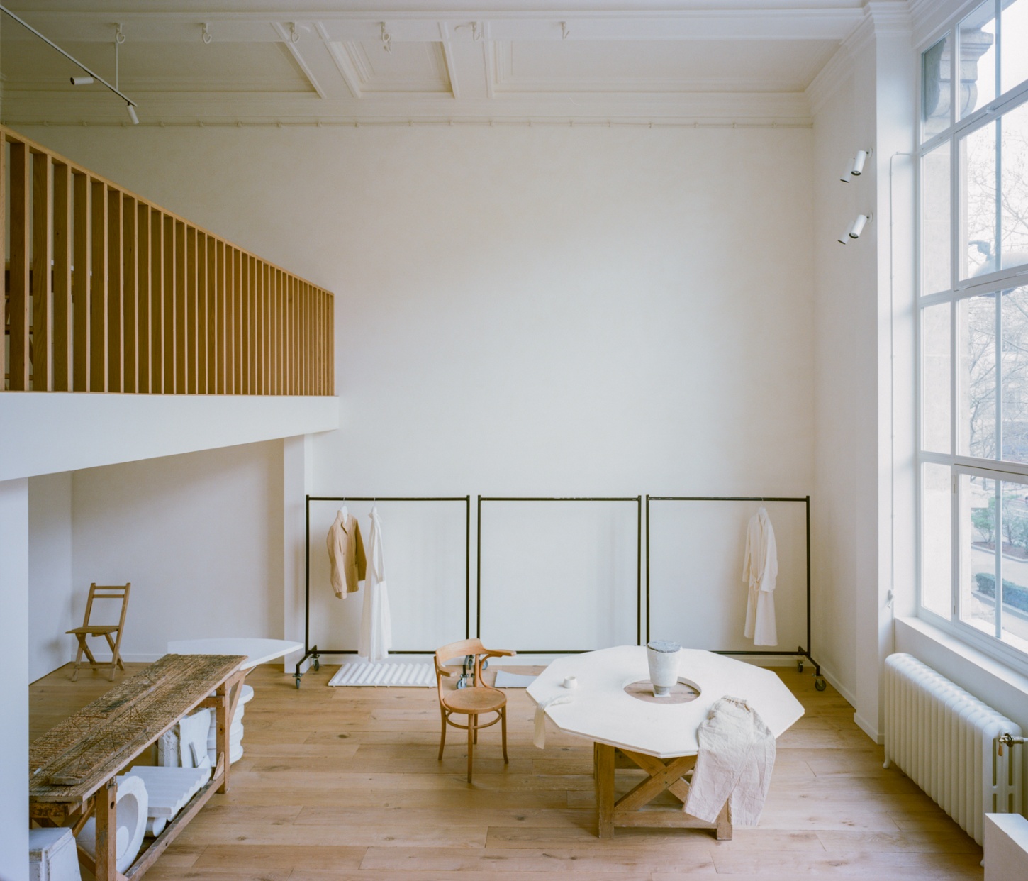 Casey Casey Showroom by Atelier NEA — The Casey Casey showroom presents a multifunctional retail environment anchored by a sculptural oak table with geometric X-frame base positioned centrally...