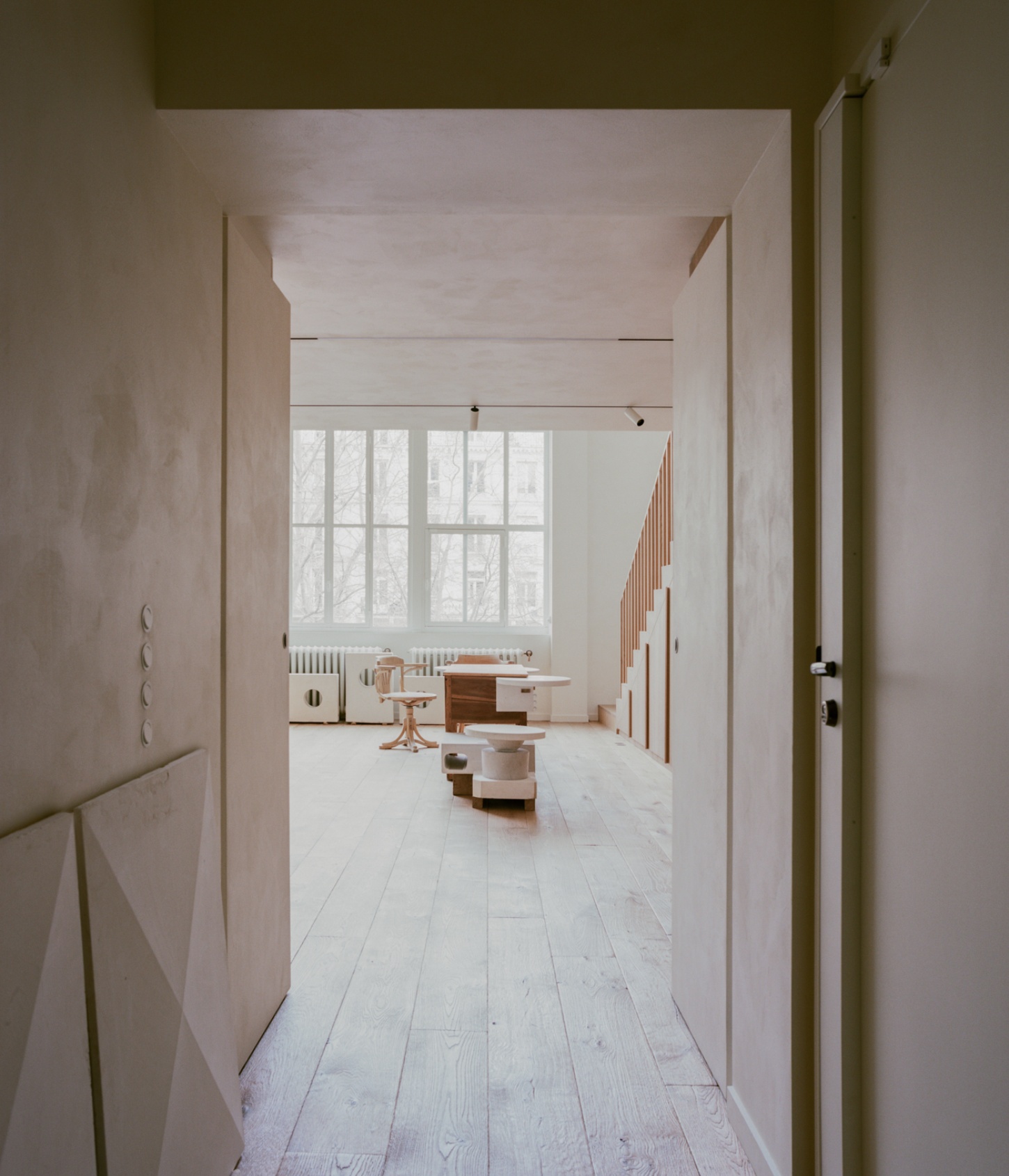Casey Casey Showroom by Atelier NEA — Axial view through a double-height passage revealing a showroom interior organized around spatial clarity and material restraint.