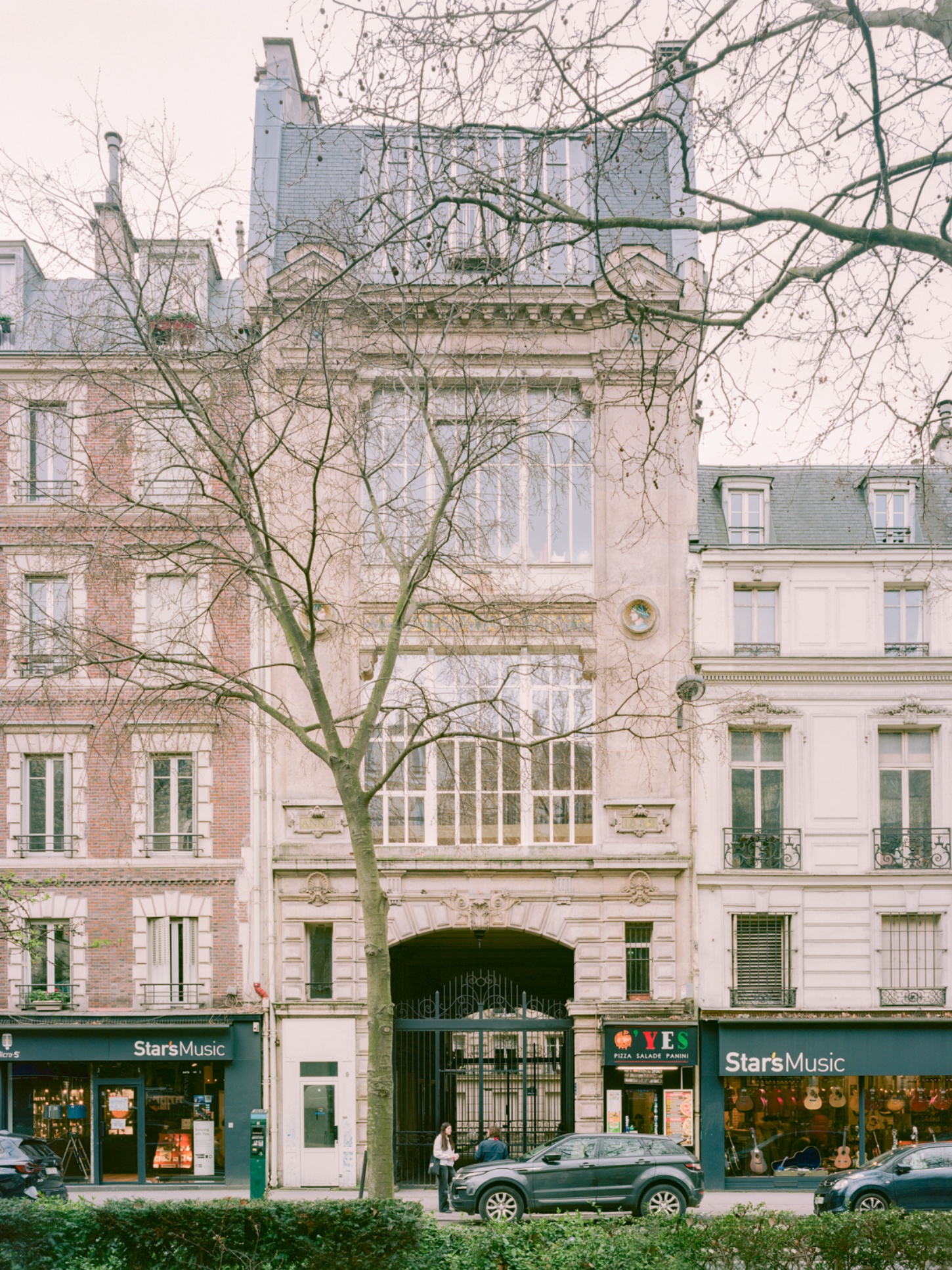 Casey Casey Showroom by Atelier NEA — The Casey Casey showroom occupies a Haussmann ground floor in Paris's 6th arrondissement, its street-facing elevation framed by a leafless plane tree in winter.