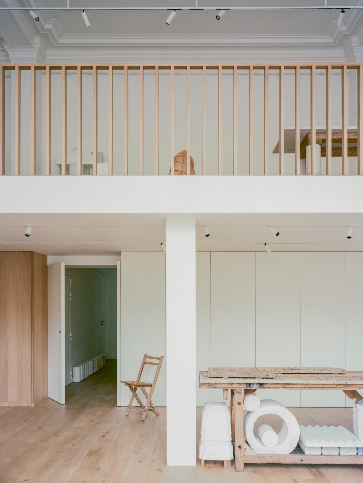Casey Casey Showroom by Atelier NEA — The showroom's upper mezzanine level features a 16-pane steel-framed window system dominating the cream-painted wall, framing views of the workspace below.