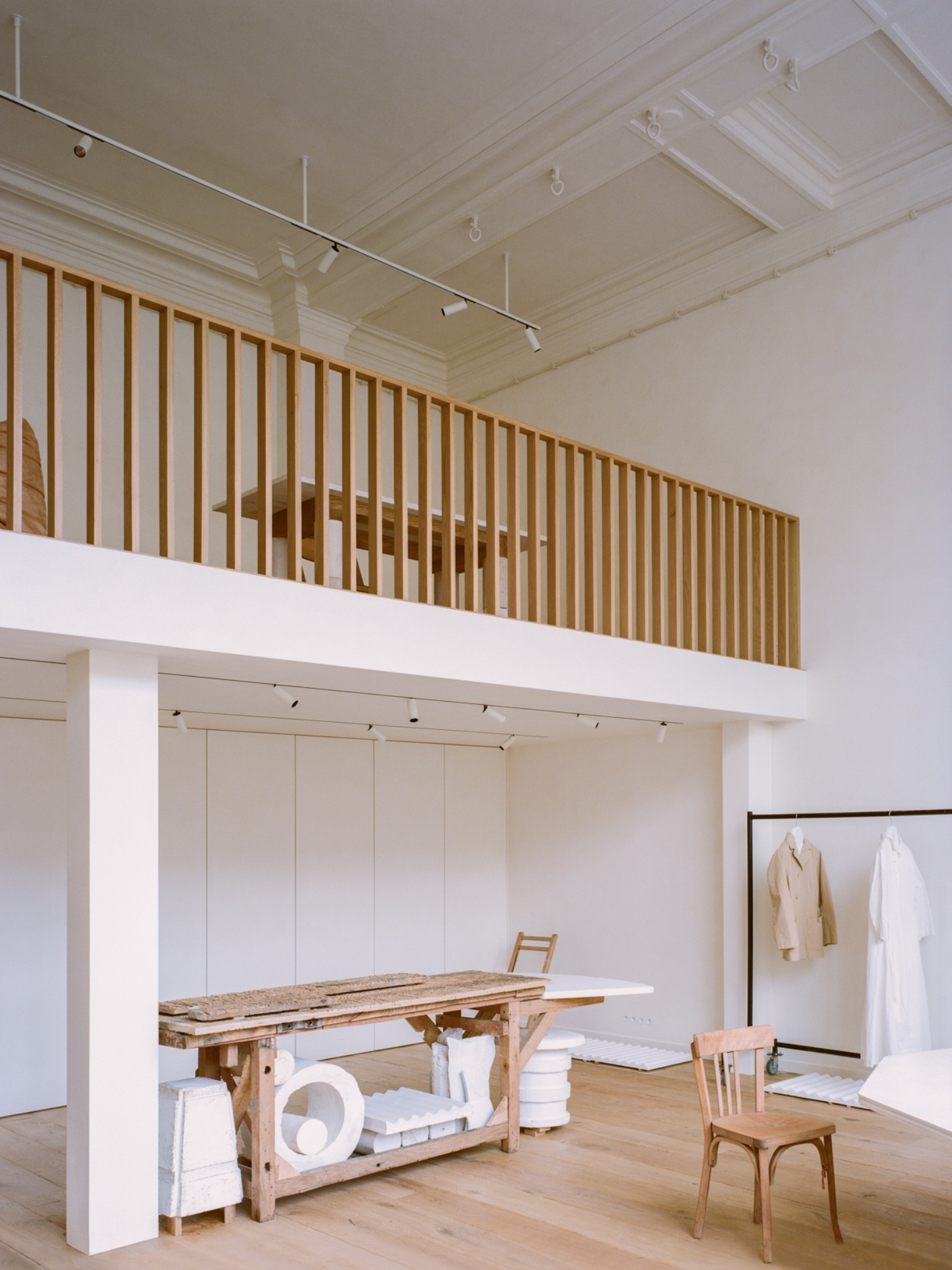 Casey Casey Showroom by Atelier NEA — The showroom's upper mezzanine level features a timber-slatted safety railing in natural oak with evenly spaced vertical members, overlooking the ground...