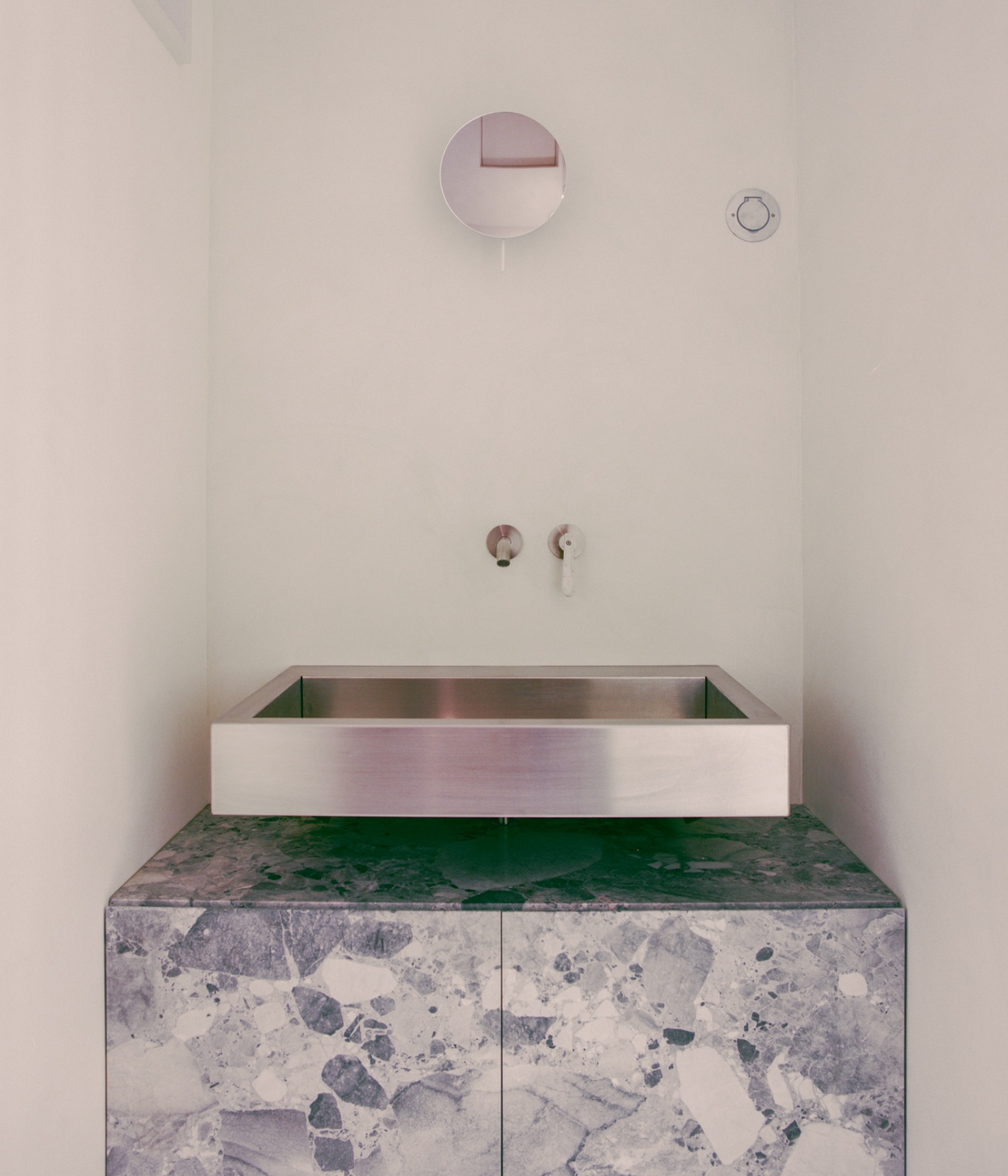 Casey Casey Showroom by Atelier NEA — A bespoke bathroom basin set within a terrazzo-topped vanity unit featuring a dramatic green and grey stone surface.