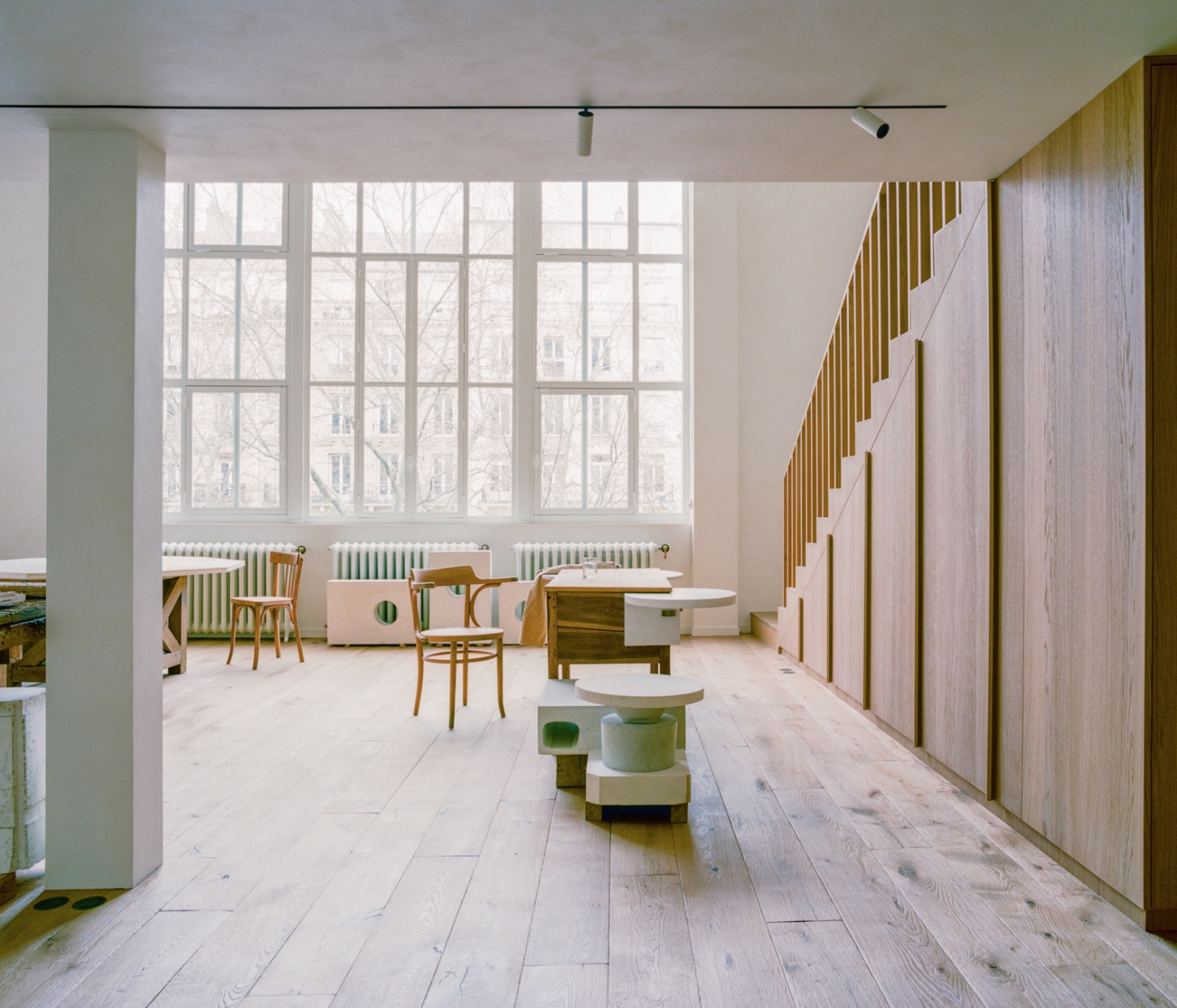 Casey Casey Showroom by Atelier NEA — A showroom interior featuring a 16-pane steel-framed window system spanning nearly the full width of the facade, flooding the space with natural light.
