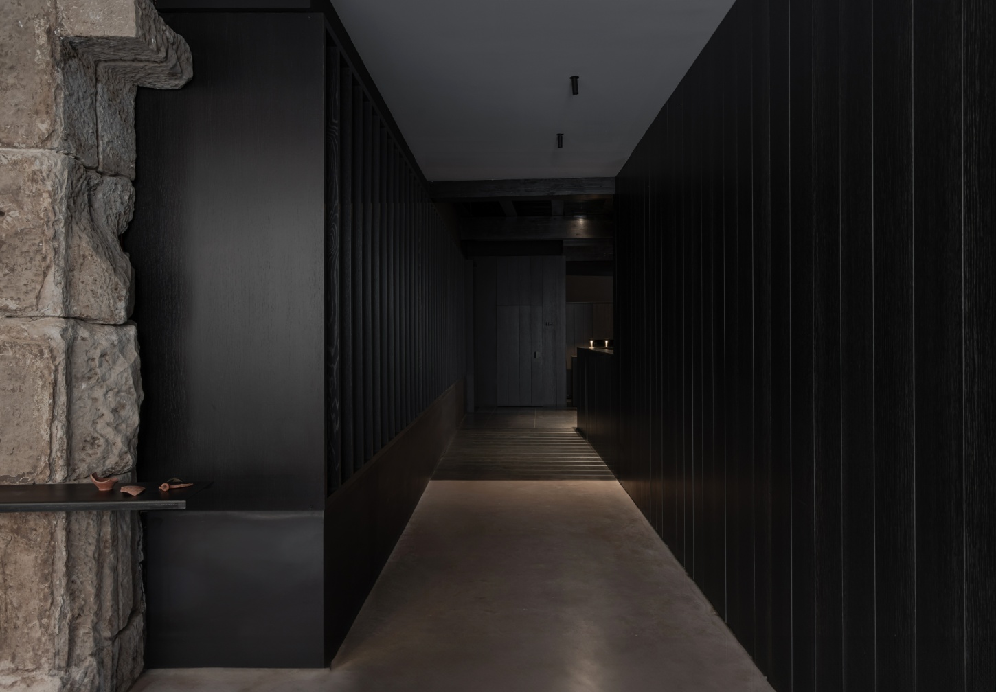 Tritium Winery by Francesc Rifé Studio — A narrow passage bisects the contemporary addition, its compressed linear perspective amplified by charred timber paneling rising on both sides.