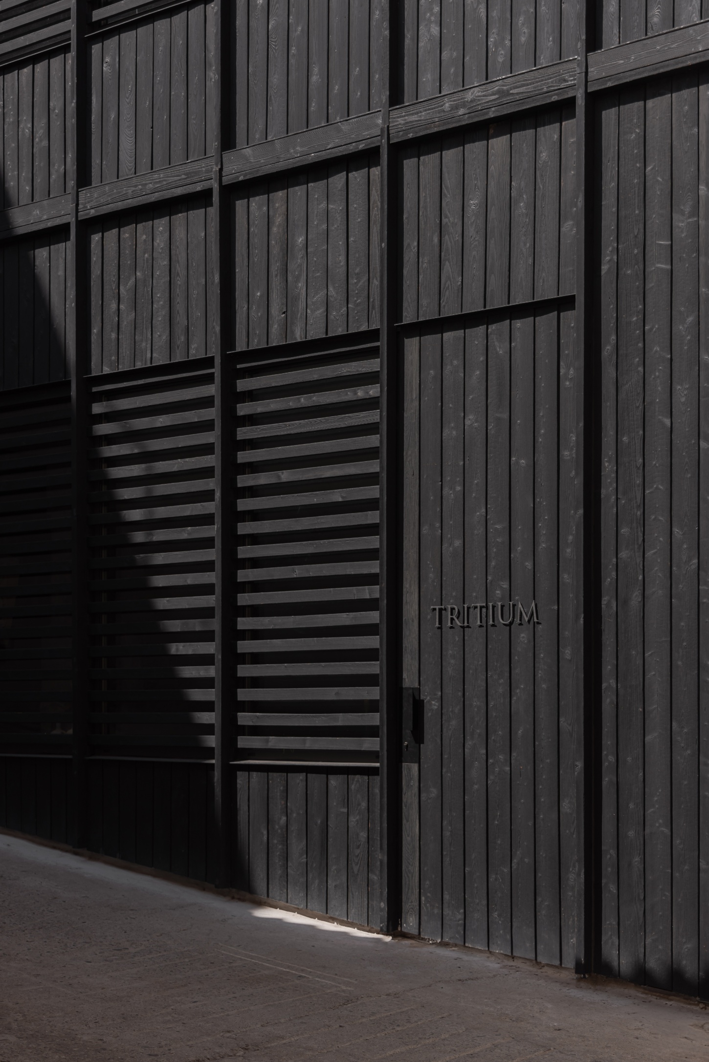 Tritium Winery by Francesc Rifé Studio — The charred timber façade of Tritium Winery's contemporary addition dominates the frame, its vertical board-formed cladding creating a monolithic presence.