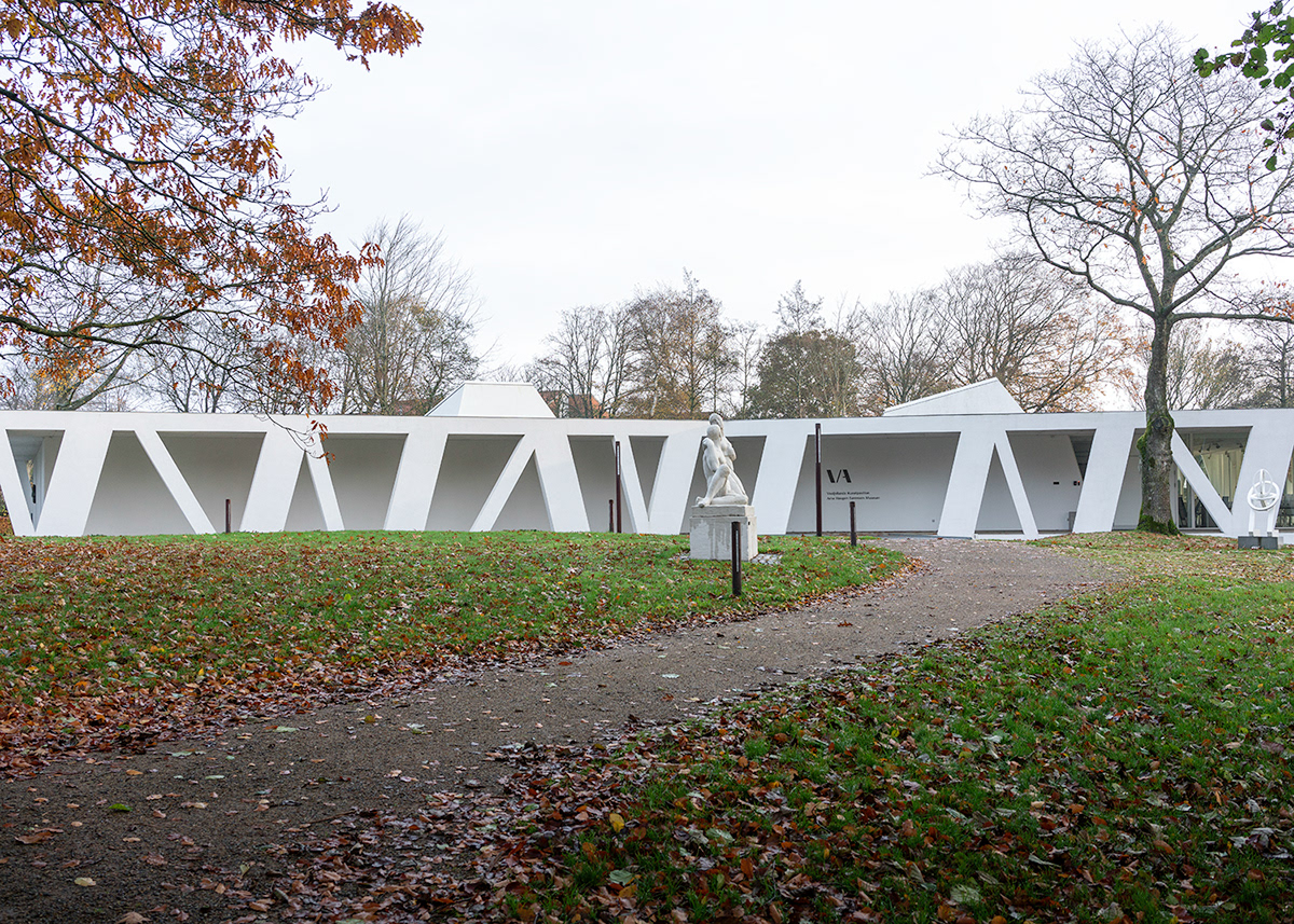 Art Pavilion in Videbaek (Vestjyllands Kunstpavillon) by Henning Larsen — The pavilion presents itself as a striking white geometric form, its diagonal lattice facade creating rhythmic vertical striations across the structure's...