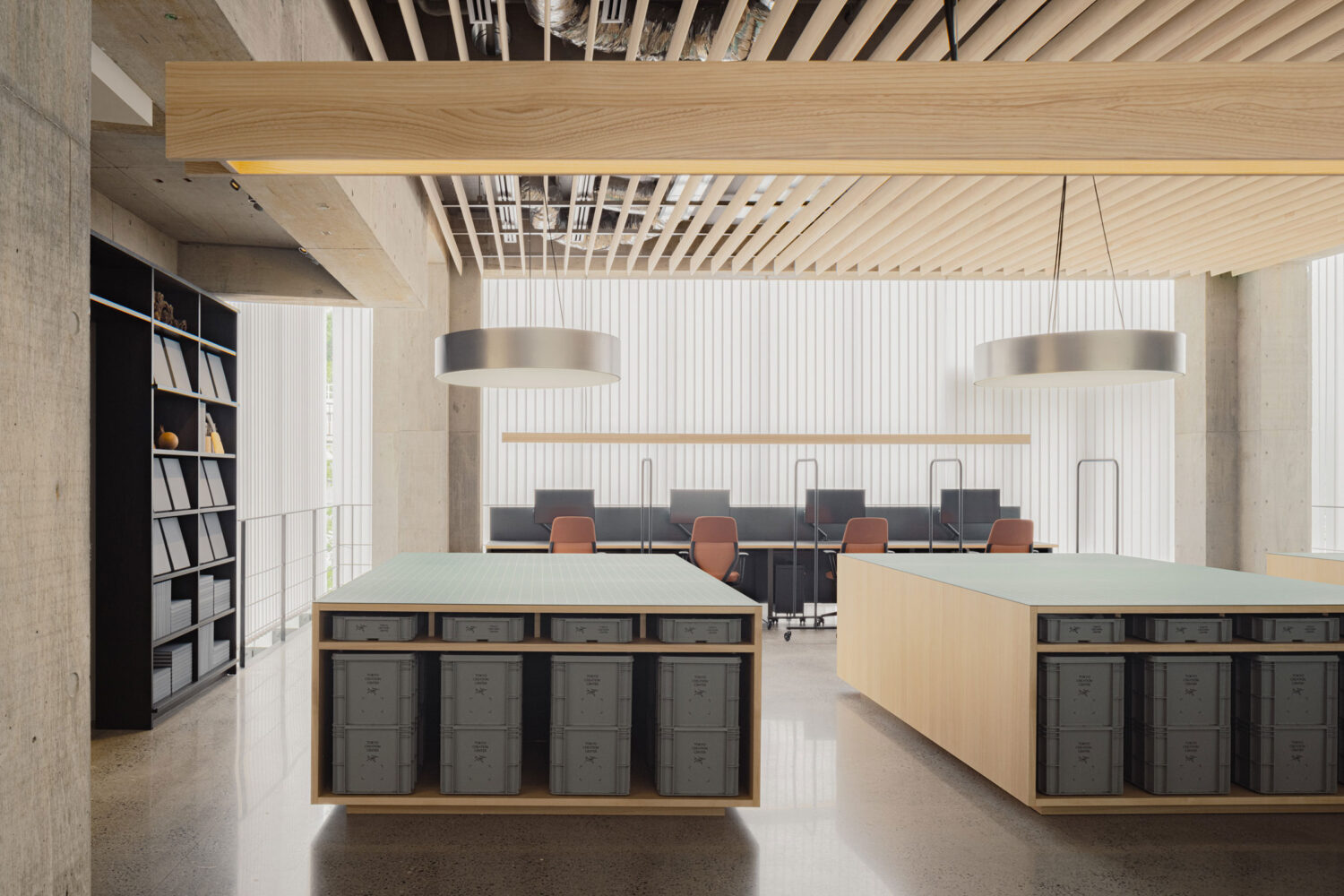 Arc’teryx Tokyo Creation Center by Torafu Architects — The creation center's interior workspace reveals a dual-island layout with light timber frames and integrated storage beneath pale-topped work surfaces.