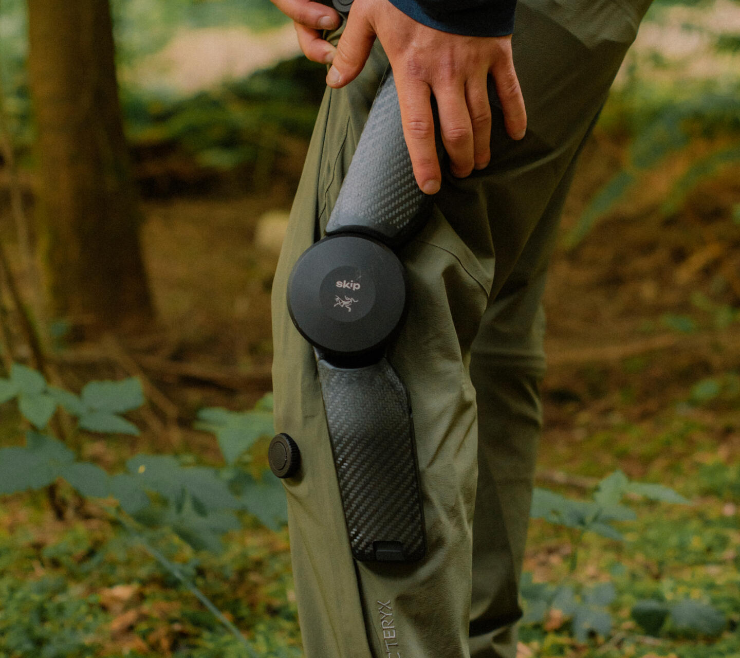 MO/GO Pants with Exoskeleton by Arc'teryx + Skip — Close-up detail of the MO/GO exoskeleton pants reveals the spherical motorized actuator at the knee joint, its black housing marked with 'skip' branding.