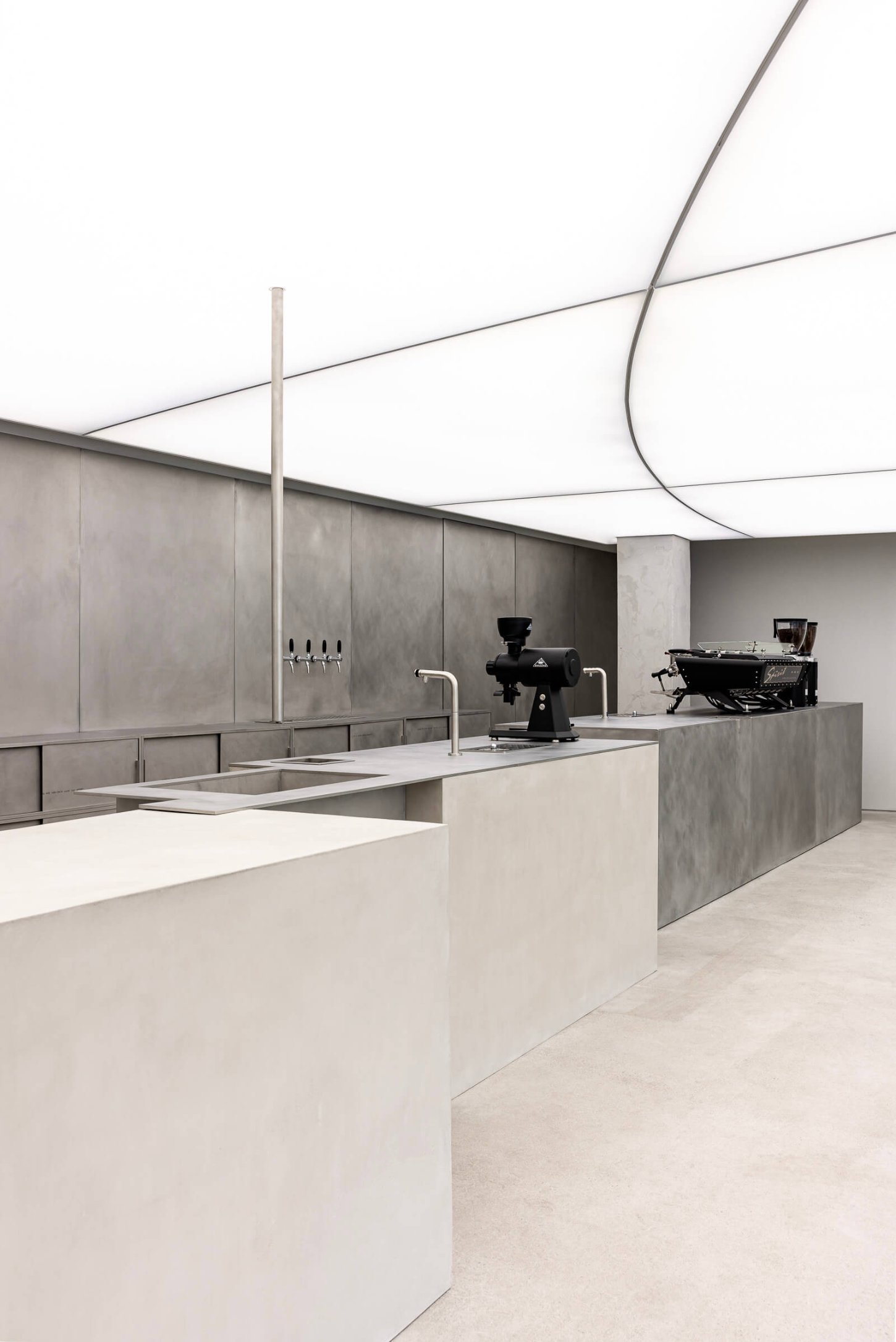 Mardi Mercredi store by Creative Studio Unravel — The counter service area features a minimalist composition anchored by a black sculptural stool with angled steel legs positioned centrally at the sink.