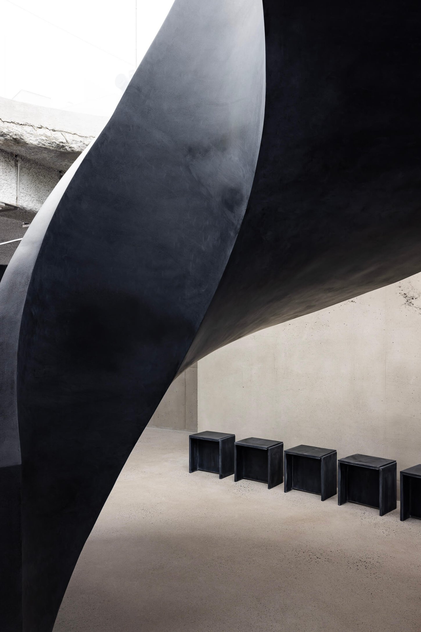 Mardi Mercredi store by Creative Studio Unravel — A sculptural interior passage dominated by a sweeping black curved form that creates dramatic spatial division.