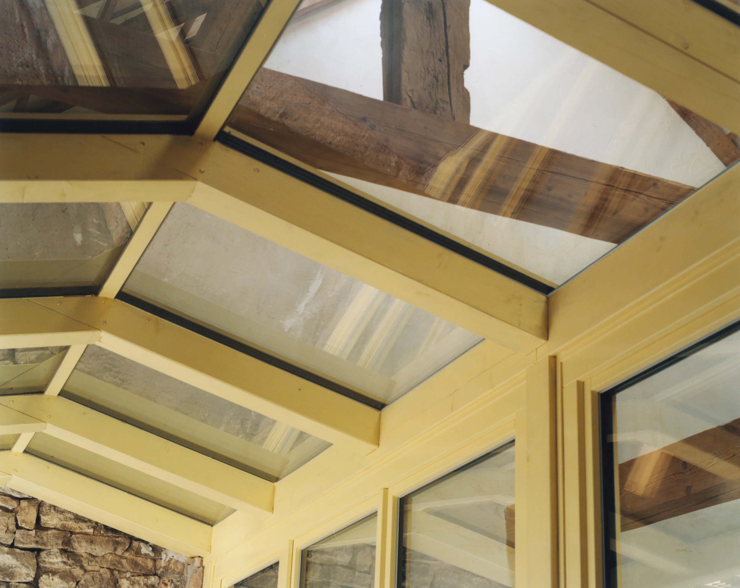 Erika and Willi's Barn by Piertzovanis Toews — A coffered ceiling of warm honey-toned timber frames skylights revealing exposed oak beams above.