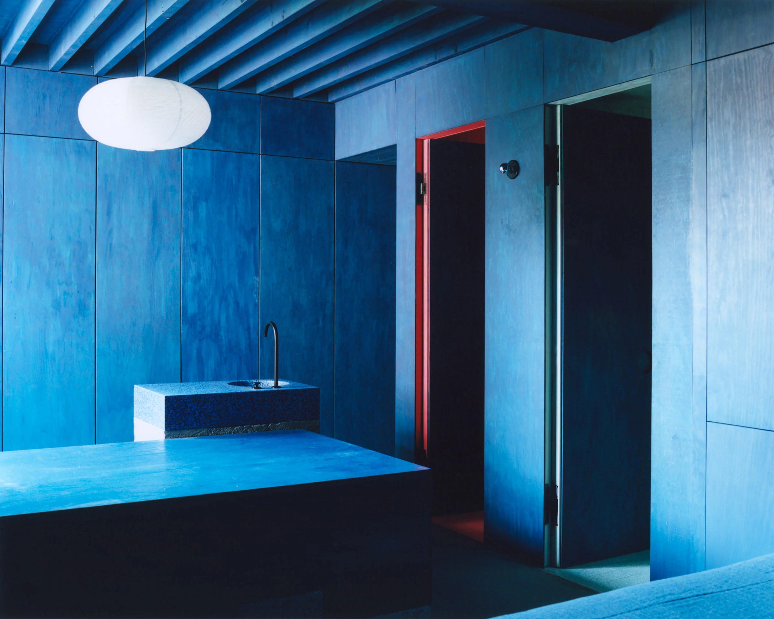 Erika and Willi's Barn by Piertzovanis Toews — A monolithic intervention in saturated cobalt blue dominates this interior volume, its surfaces reflecting the cool overhead lighting in subtle gradations.